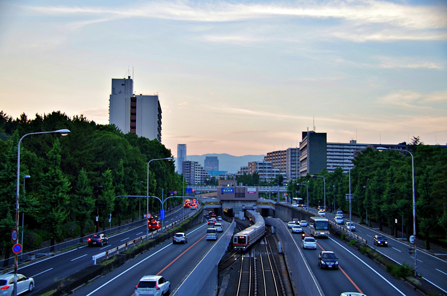 Städtische Landschaft bei Dämmerung mit Straßen- und Eisenbahnkreuzung