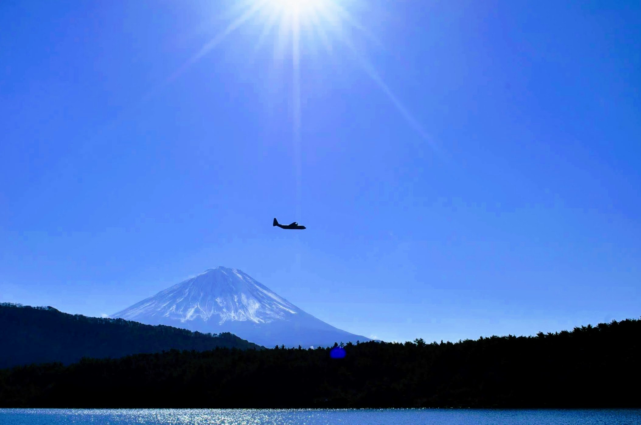 青空の下で富士山と湖畔に飛行機雲