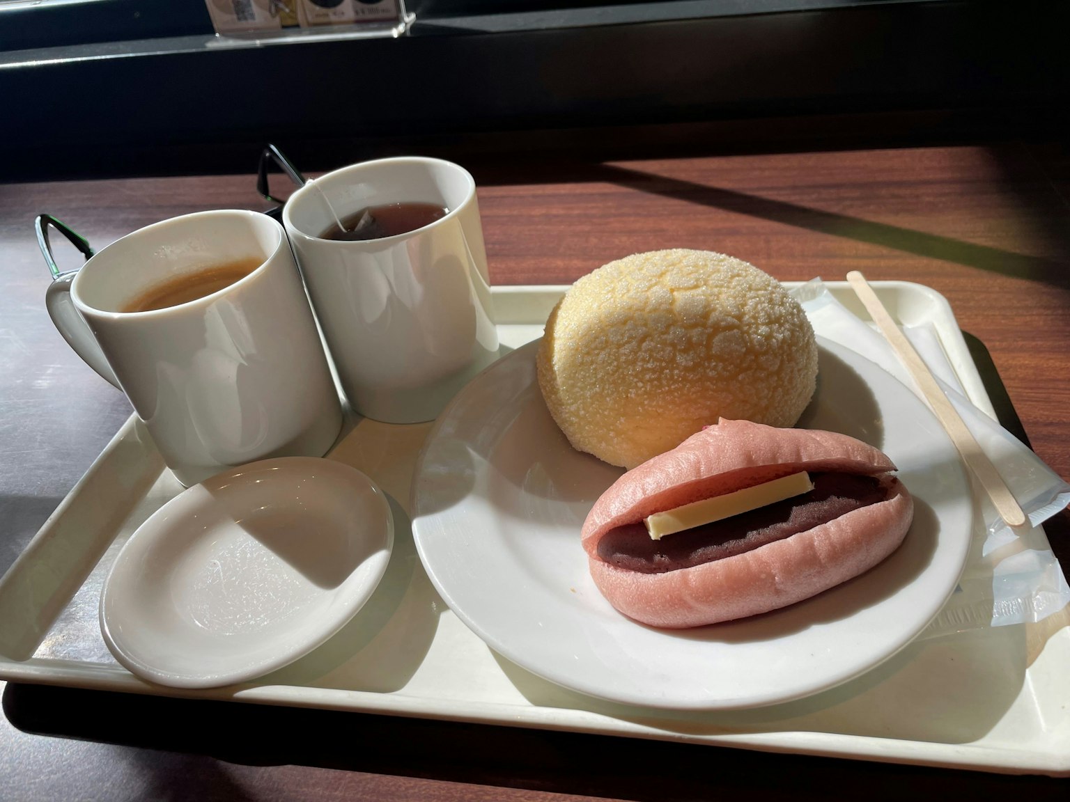 A unique dessert shaped like lips filled with red bean paste alongside a soft bun and two cups of tea