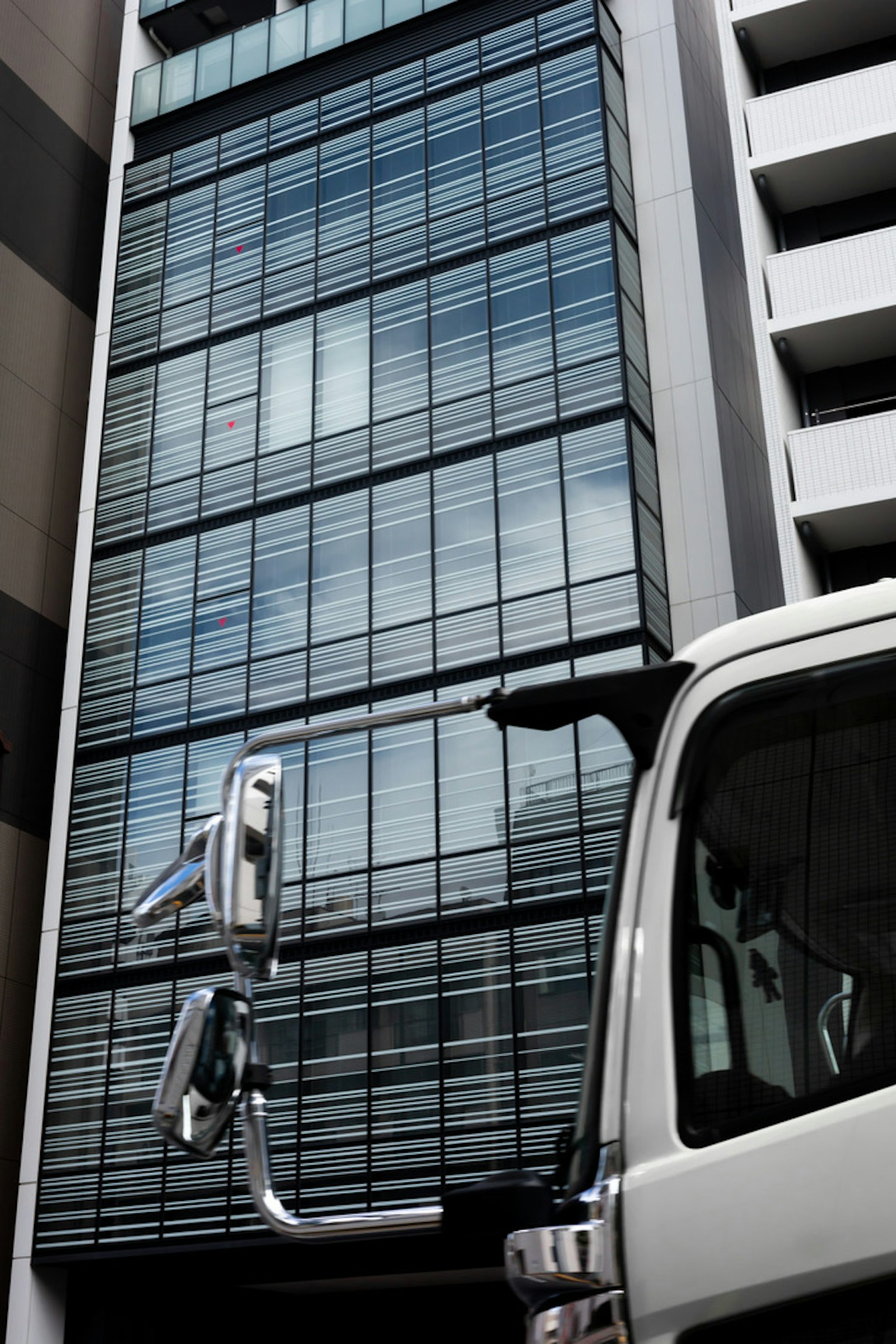 Urban scene featuring a glass building and part of a truck