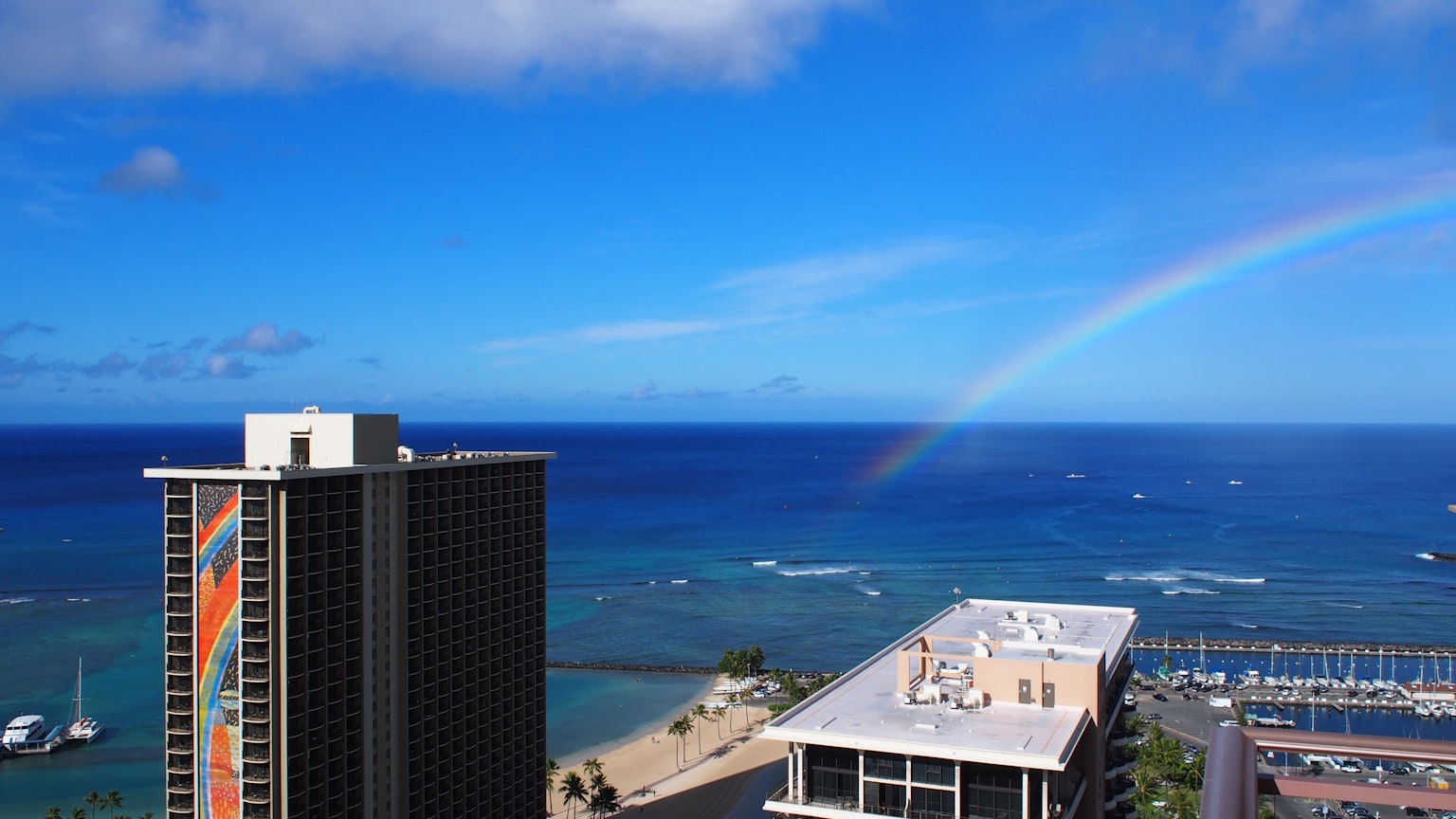 View of a high-rise building and blue ocean with a rainbow