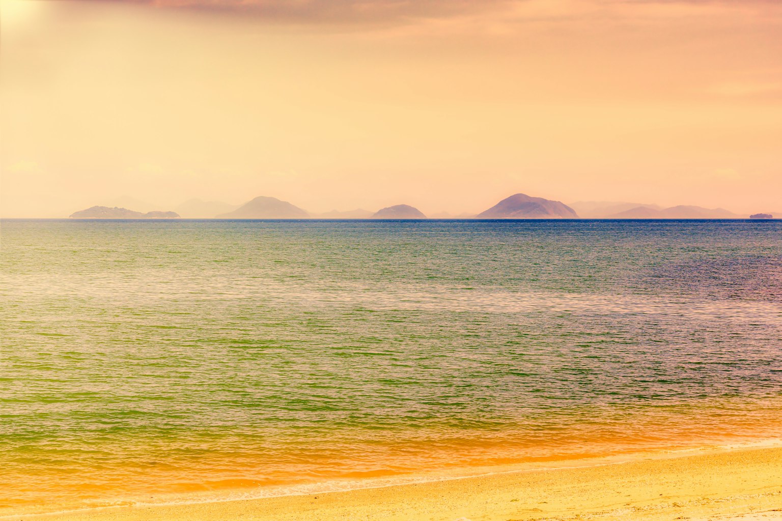Escena de playa serena con islas distantes en el horizonte