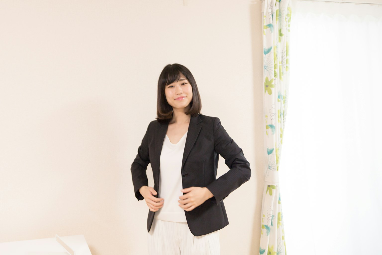 Una mujer de pie en una habitación ajustando su blazer