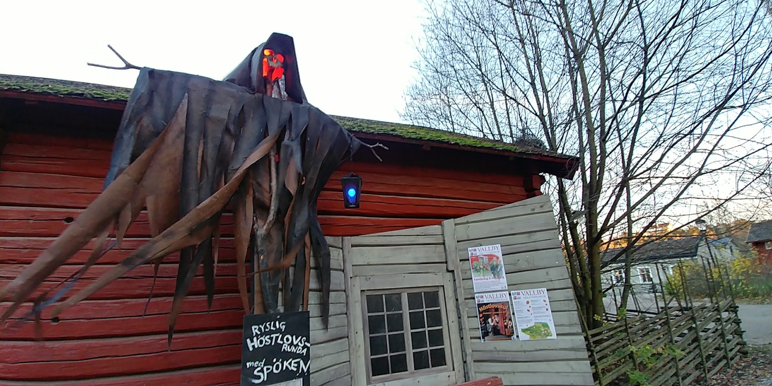 Una decoración de fantasma colgando de una casa con una puerta de madera