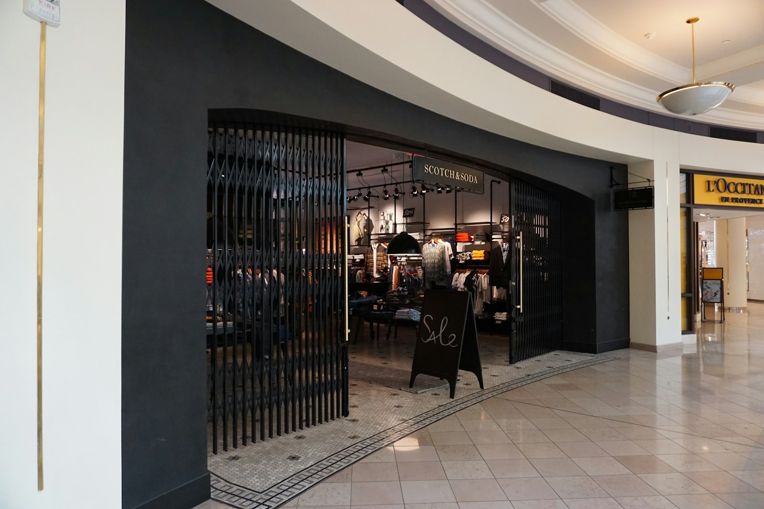 Entrée d'un magasin dans un centre commercial avec une porte à barreaux distinctive