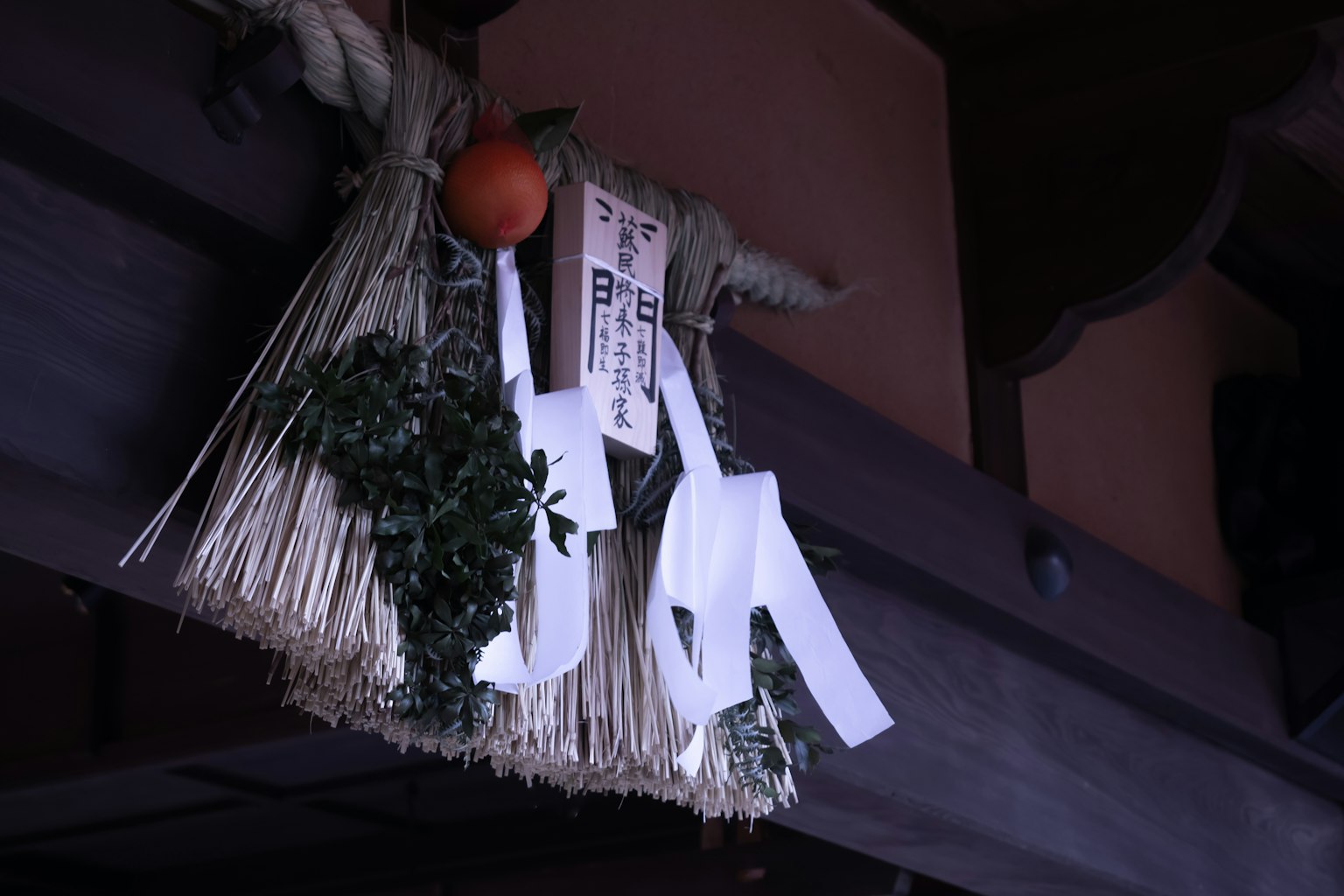 Paglia decorativa e arancia con carta bianca appesa a una trave