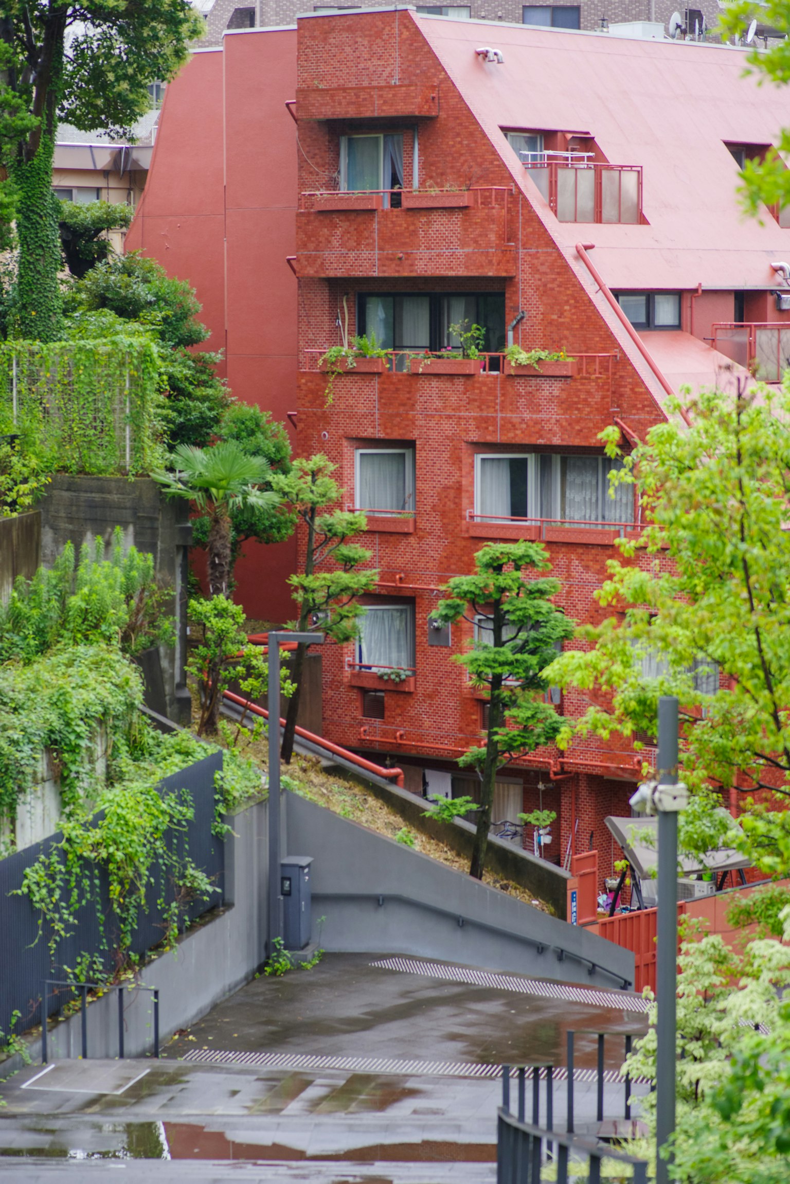 Edificio rosso angolare con piante verdi nella scena