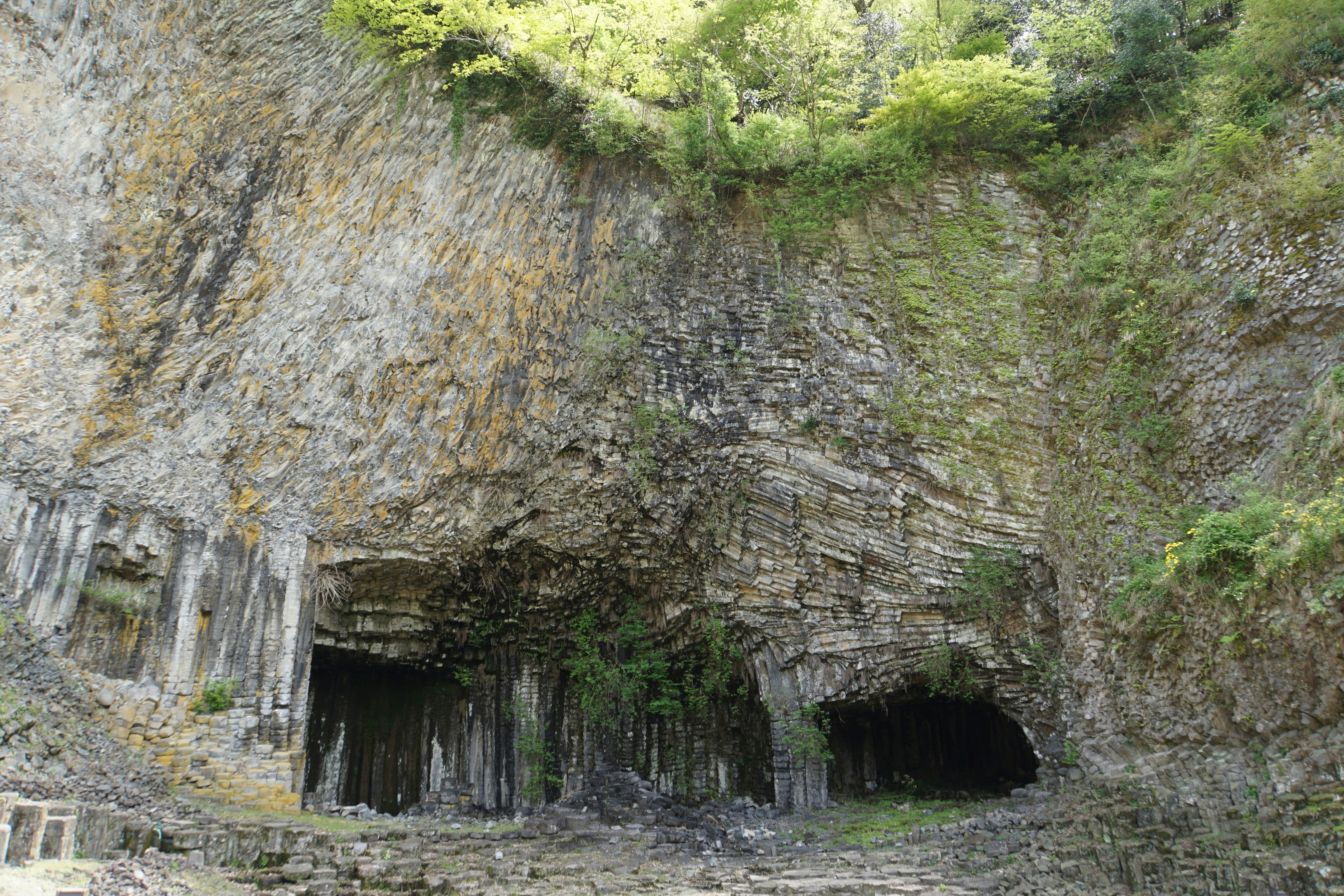 ingresso di una grotta incorniciato da una scogliera rocciosa e interno in pietra