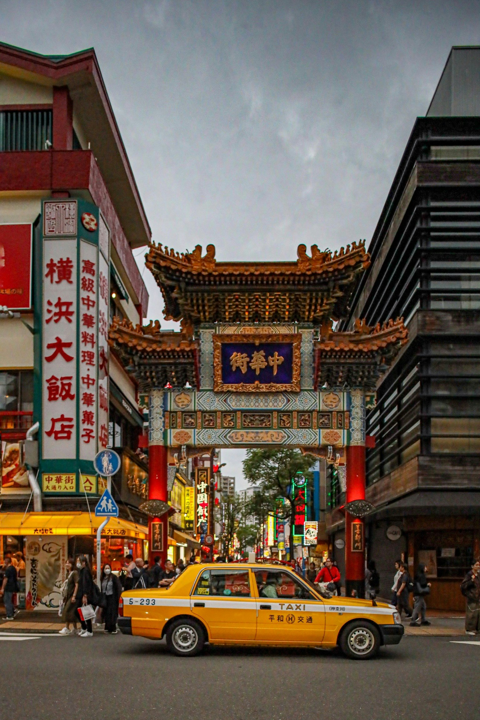 Belebte Straße mit einem chinesischen Tor und einem Taxi in Yokohama Chinatown