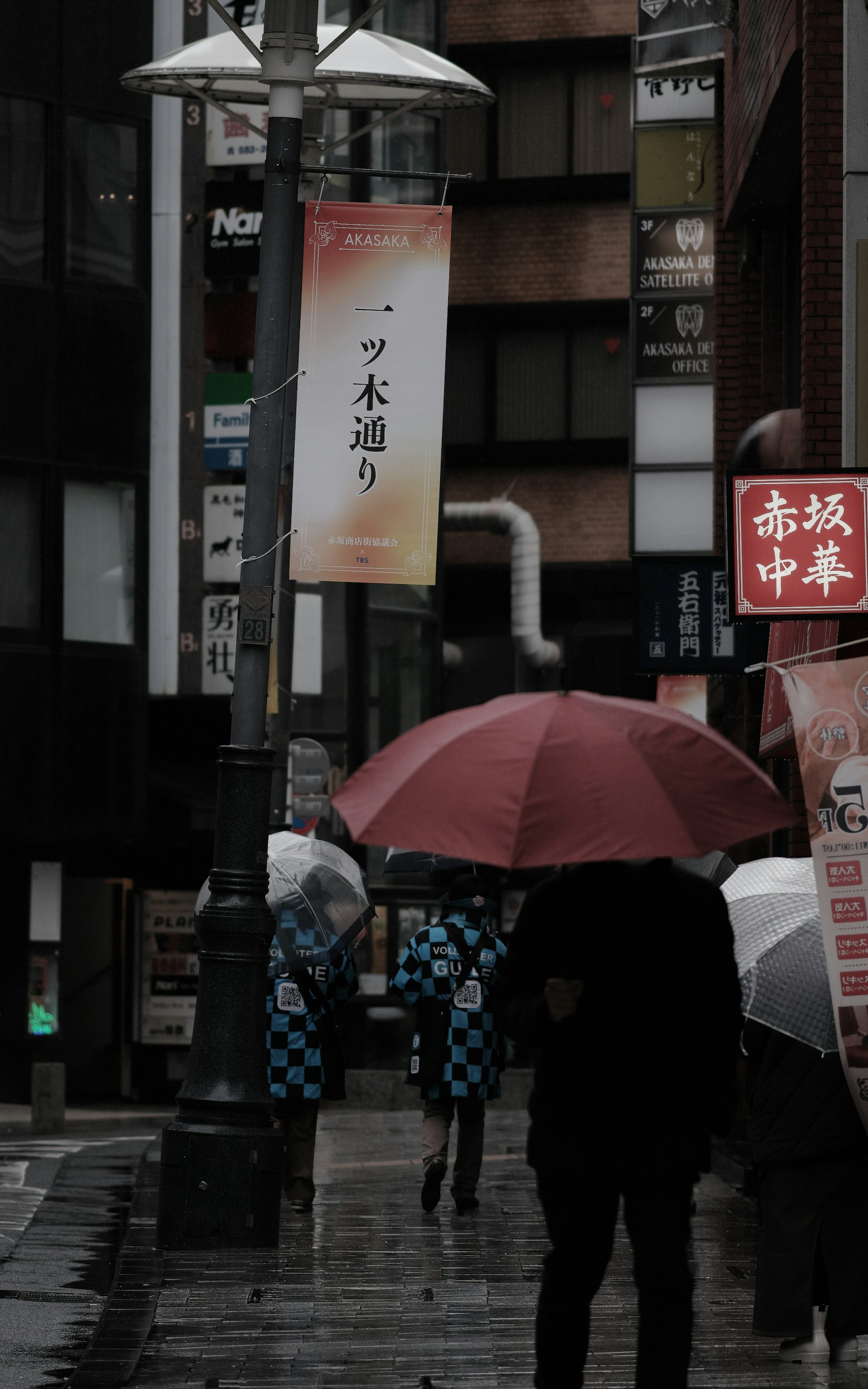 City street scene with people walking under umbrellas in the rain