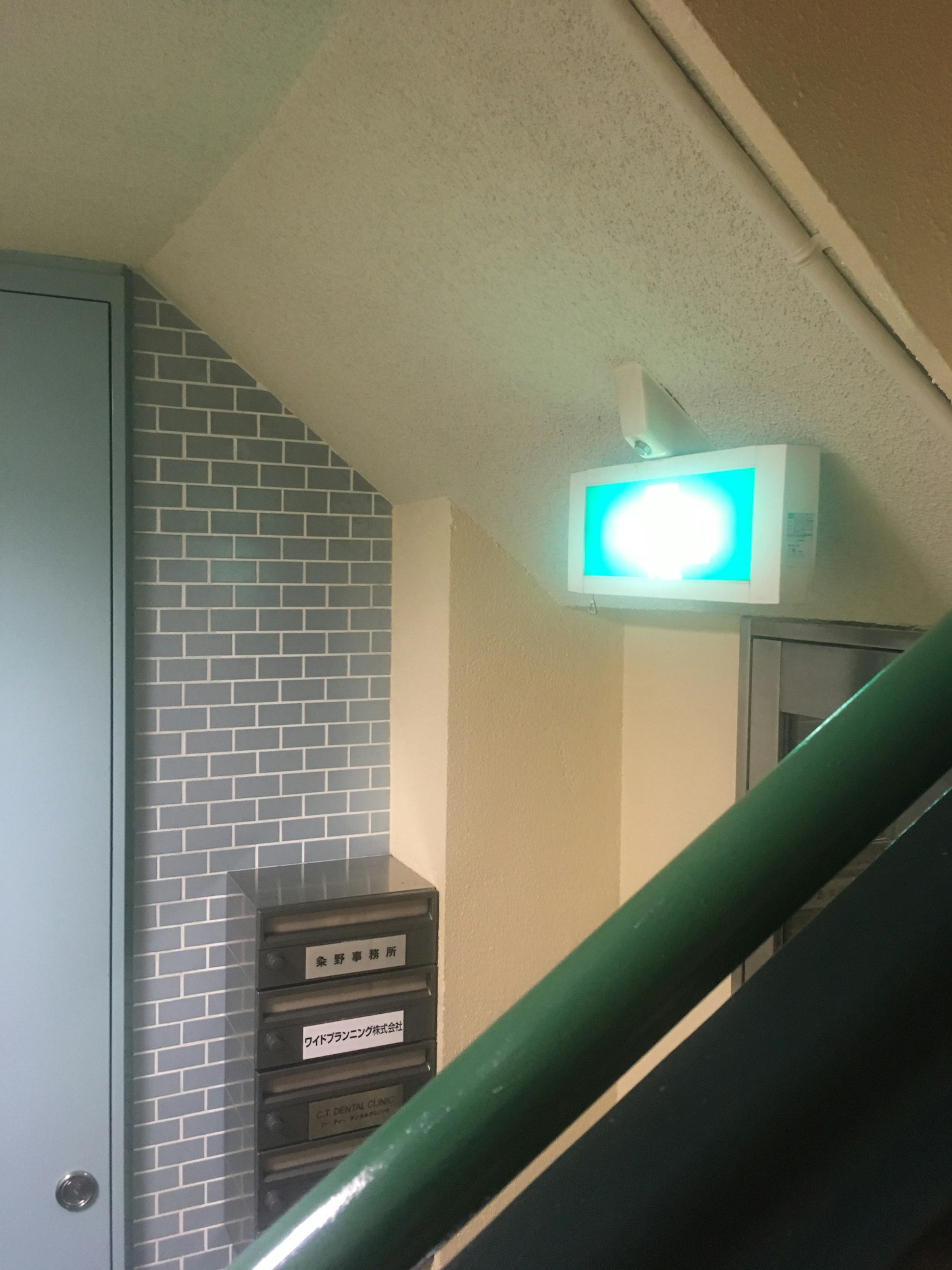 楼梯角落的绿色紧急出口标志和砖墙