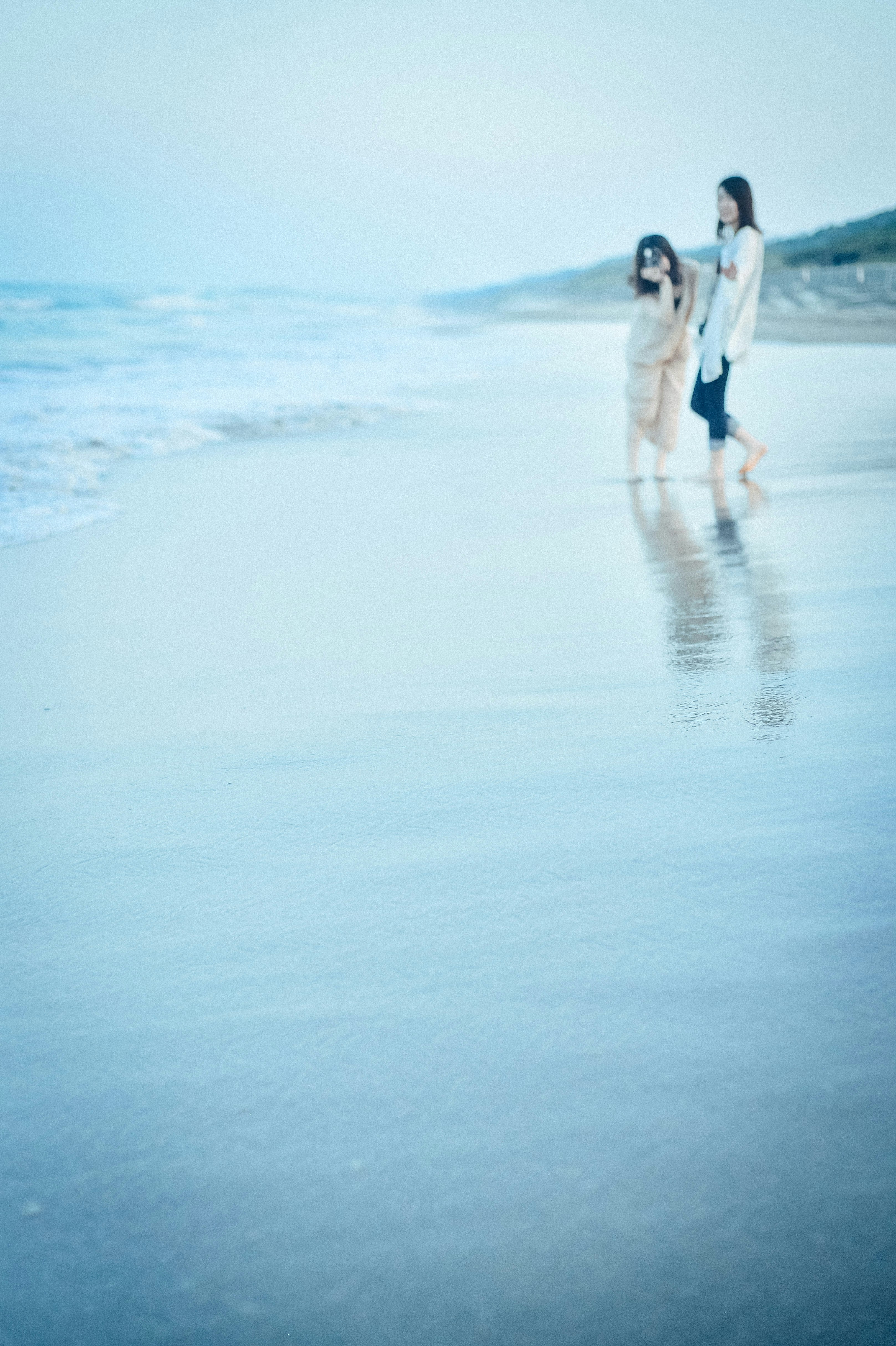 silhouetted people walking along a blue seaside beach