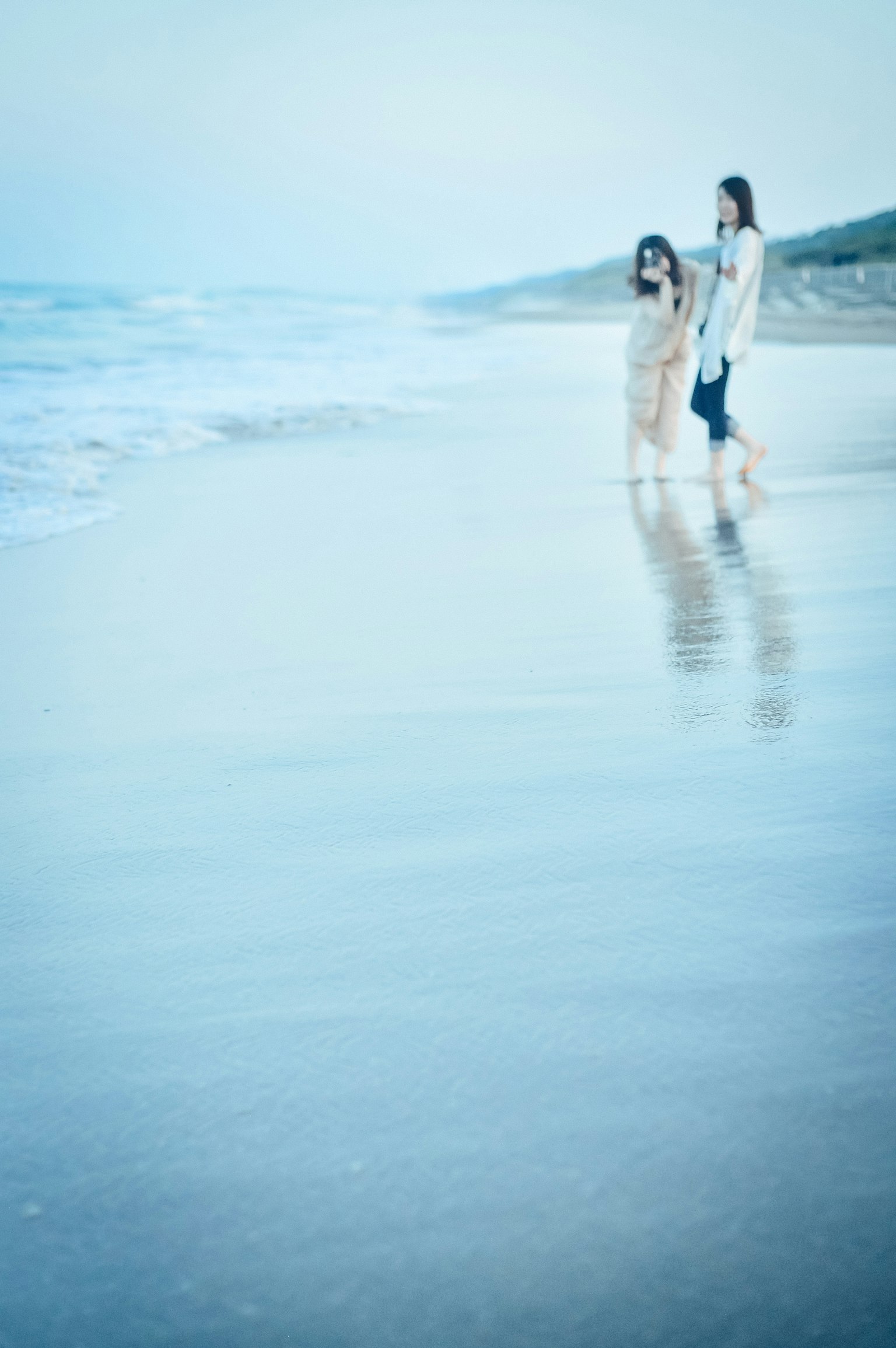 Silueta de un padre y un hijo caminando en la playa con reflejos de olas