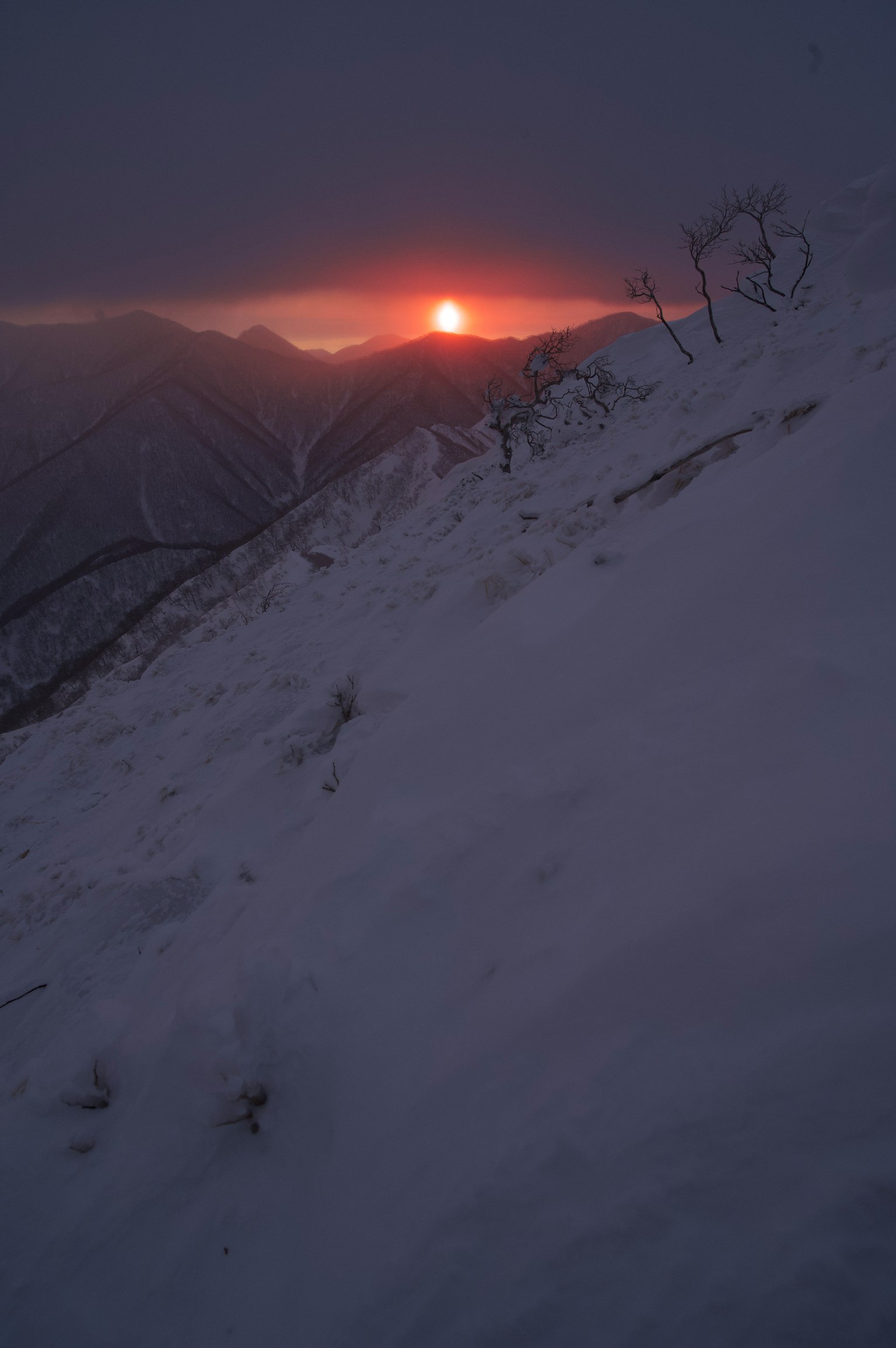 雪覆盖的山坡上夕阳西下，光线戏剧性