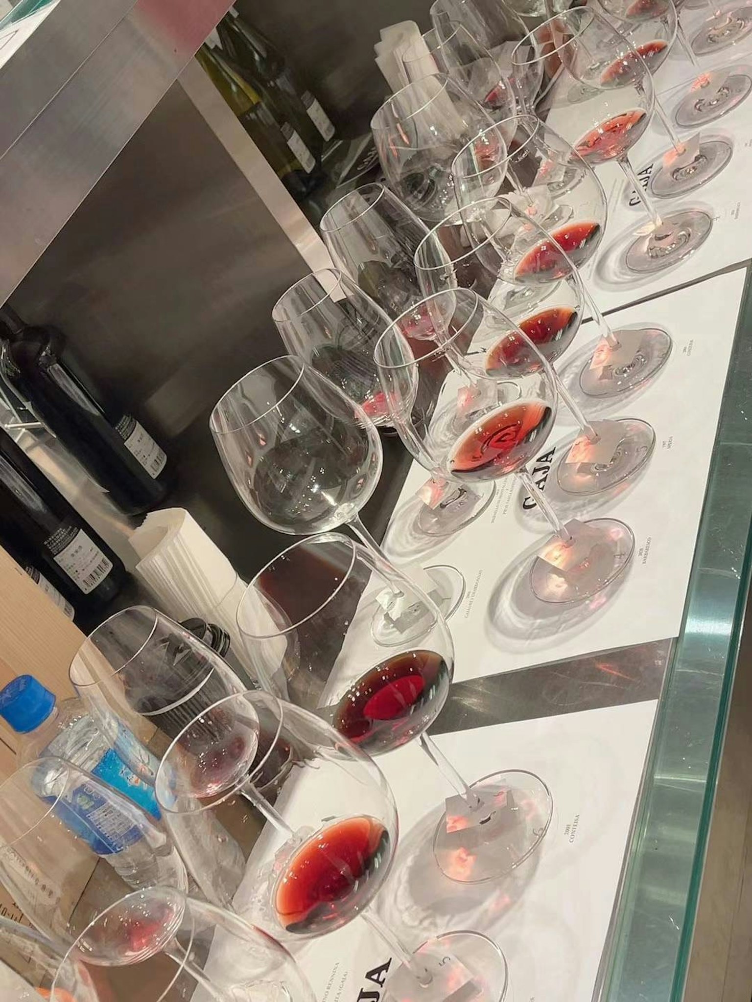 Una fila di bicchieri di vino riempiti di vino rosso su un bancone