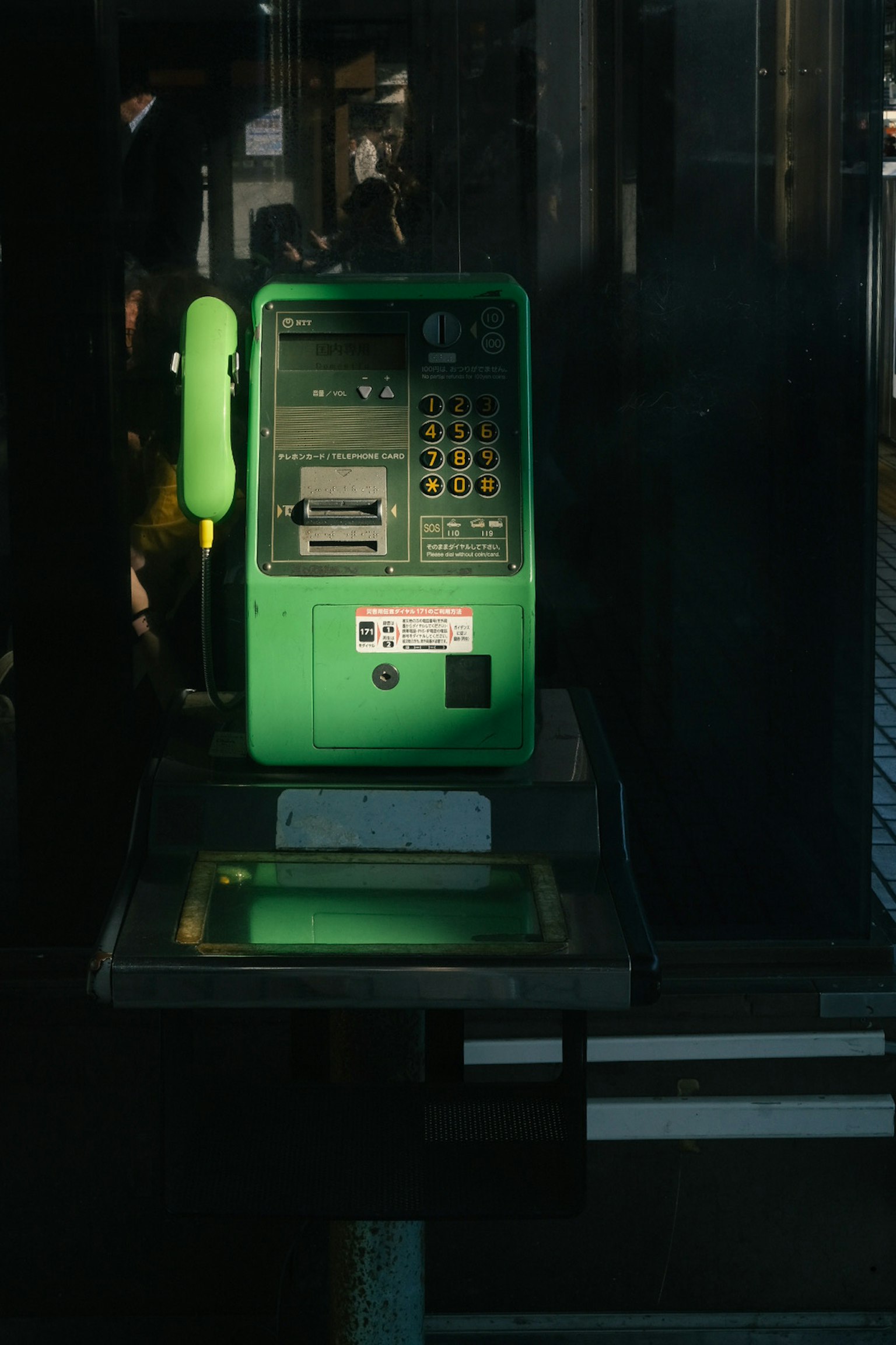 Immagine di un telefono pubblico verde con tastiera e ricevitore