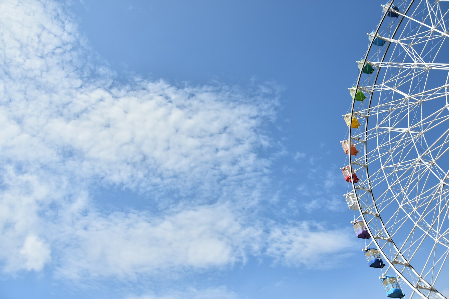 Vue latérale d'une grande roue sous un ciel bleu capsules colorées alignées