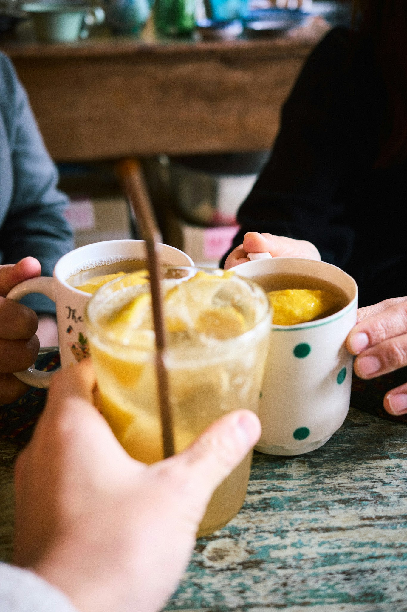 カフェのテーブルで手を伸ばす人々とスープカップ
