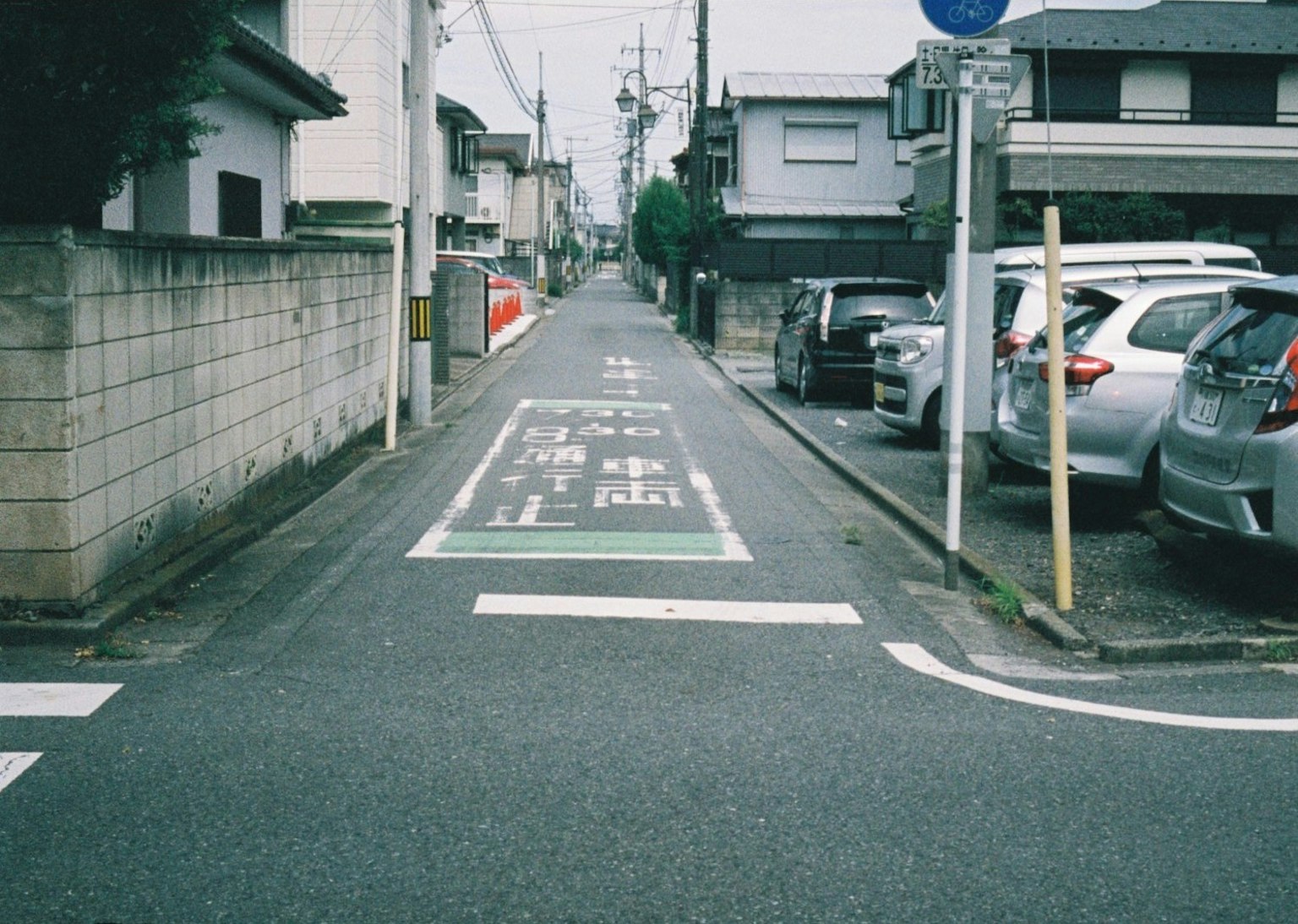 狭窄的住宅街道和可见的房屋与停放的汽车