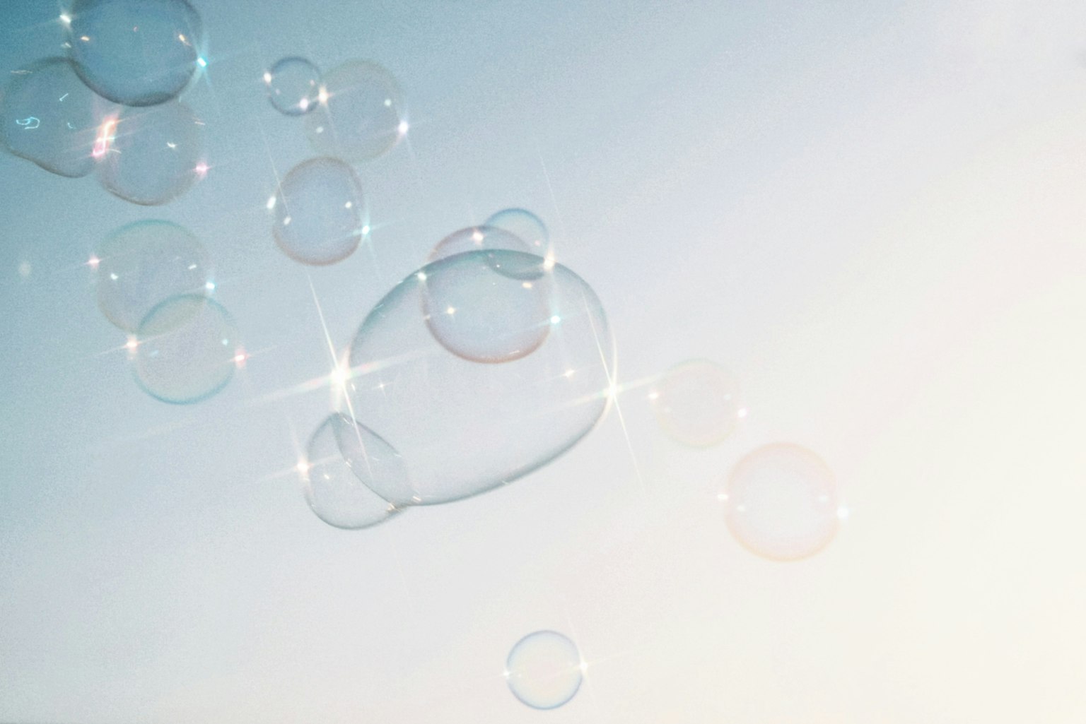 Transparente Seifenblasen, die in einem blauen Himmel mit Lichtreflexionen schweben