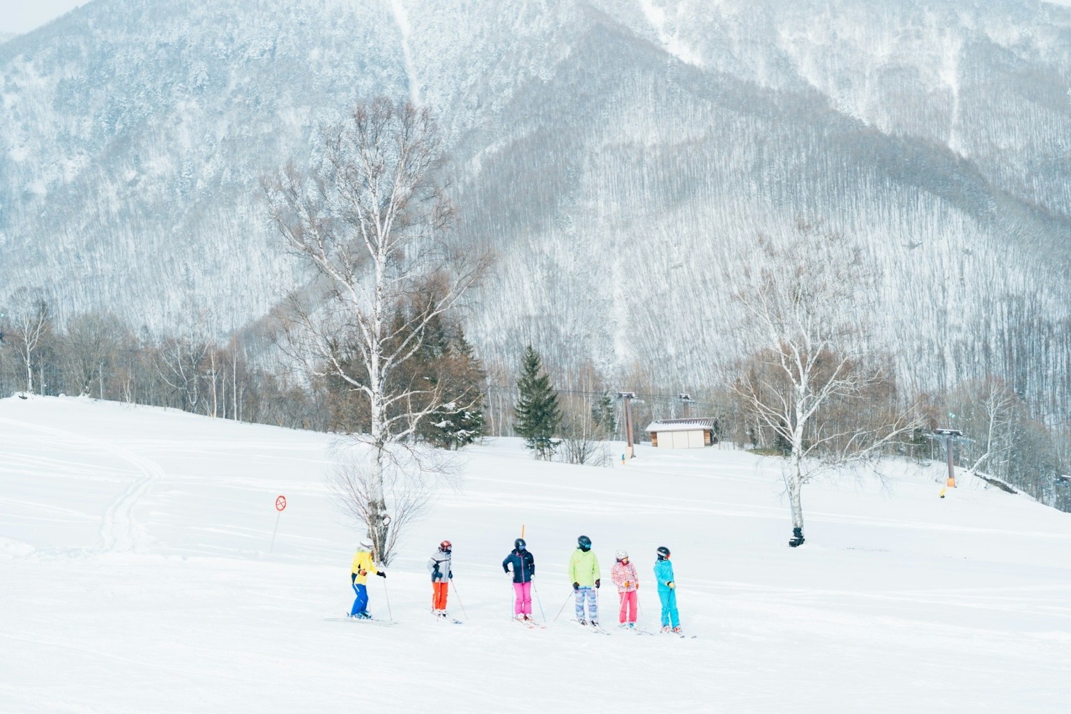 一群穿着色彩鲜艳滑雪服的孩子在雪地和山脉上