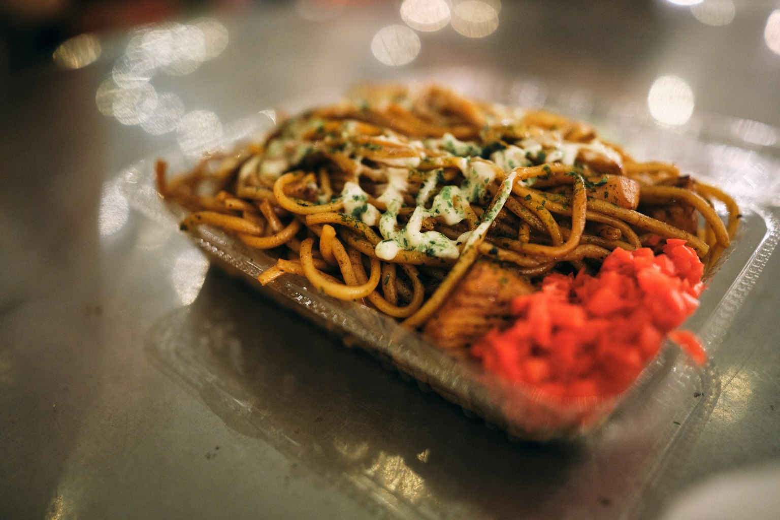A dish of yakisoba noodles topped with sauce and pickled ginger
