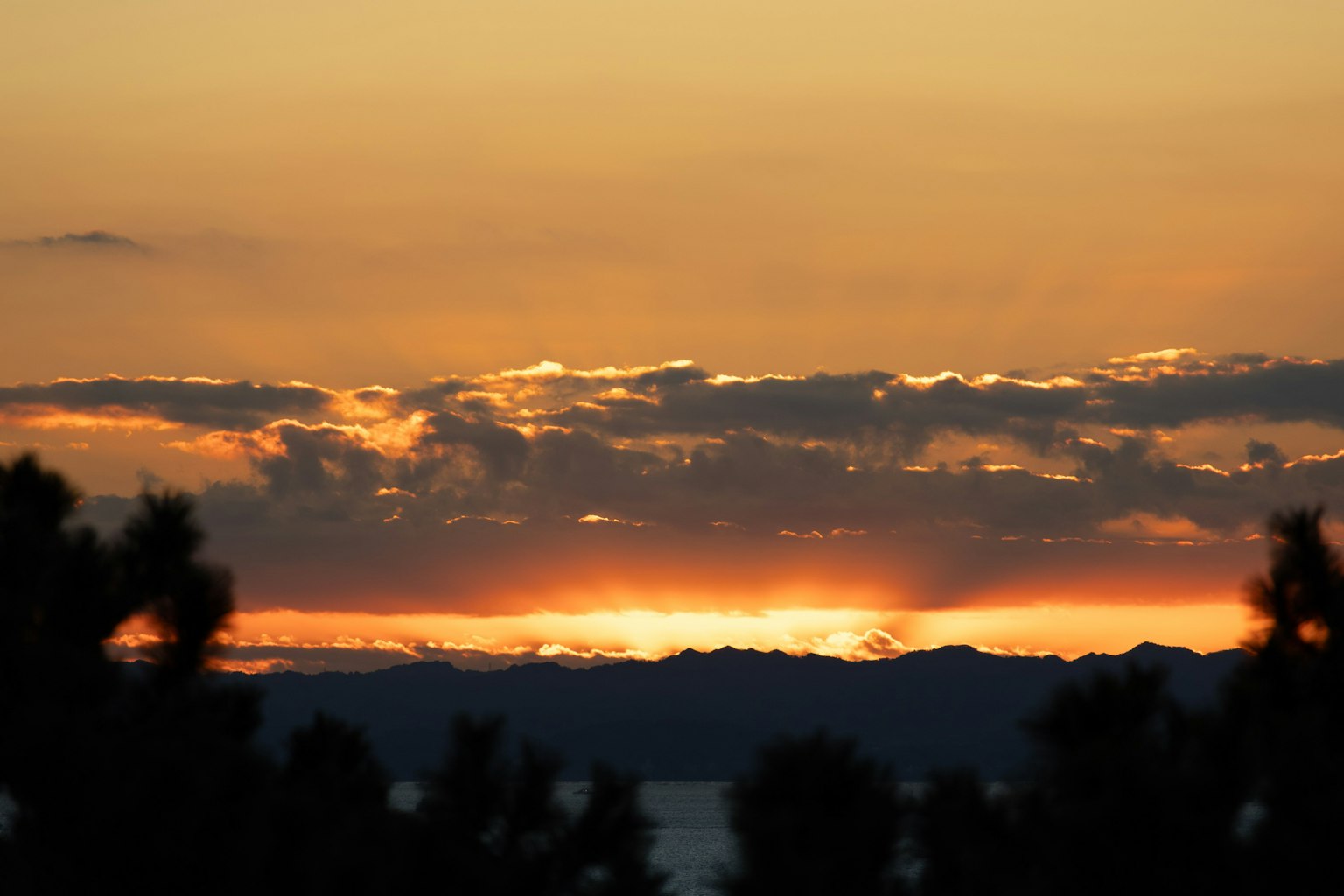 Bellissimo paesaggio al tramonto con silhouette di montagne e cielo arancione