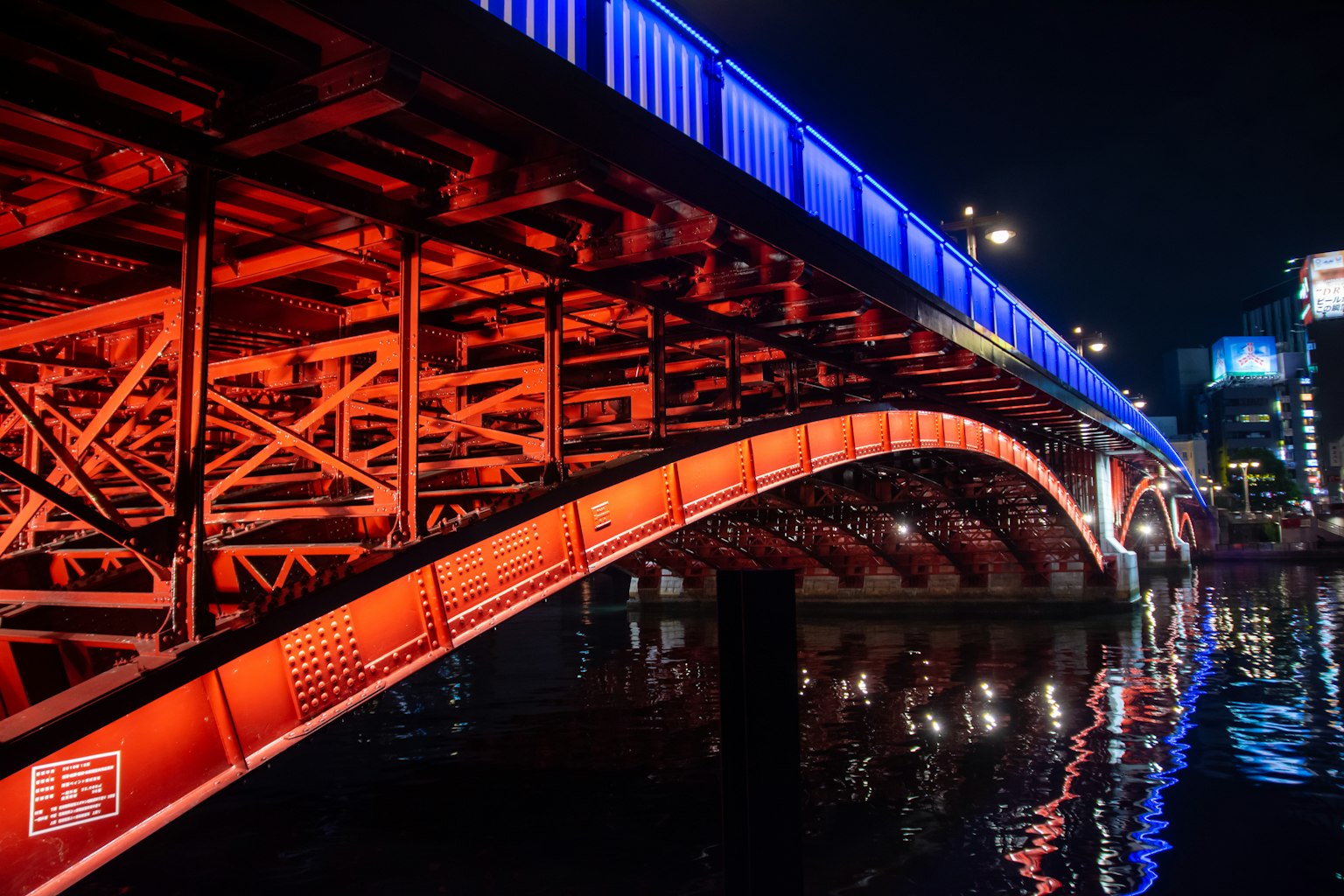Hermoso arco de un puente iluminado por la noche con reflejos en el agua