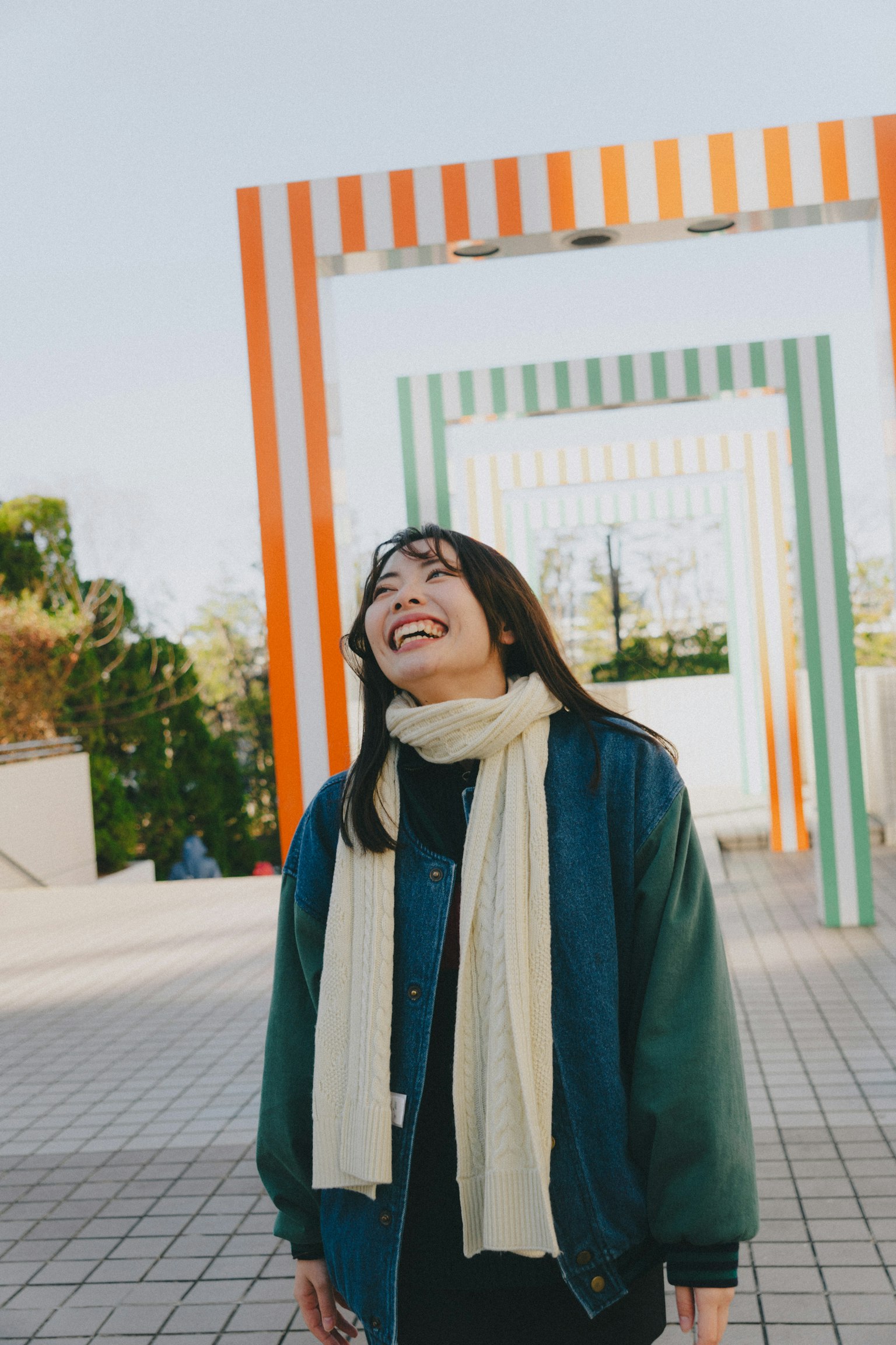 Una donna sorridente in piedi tra archi striati colorati