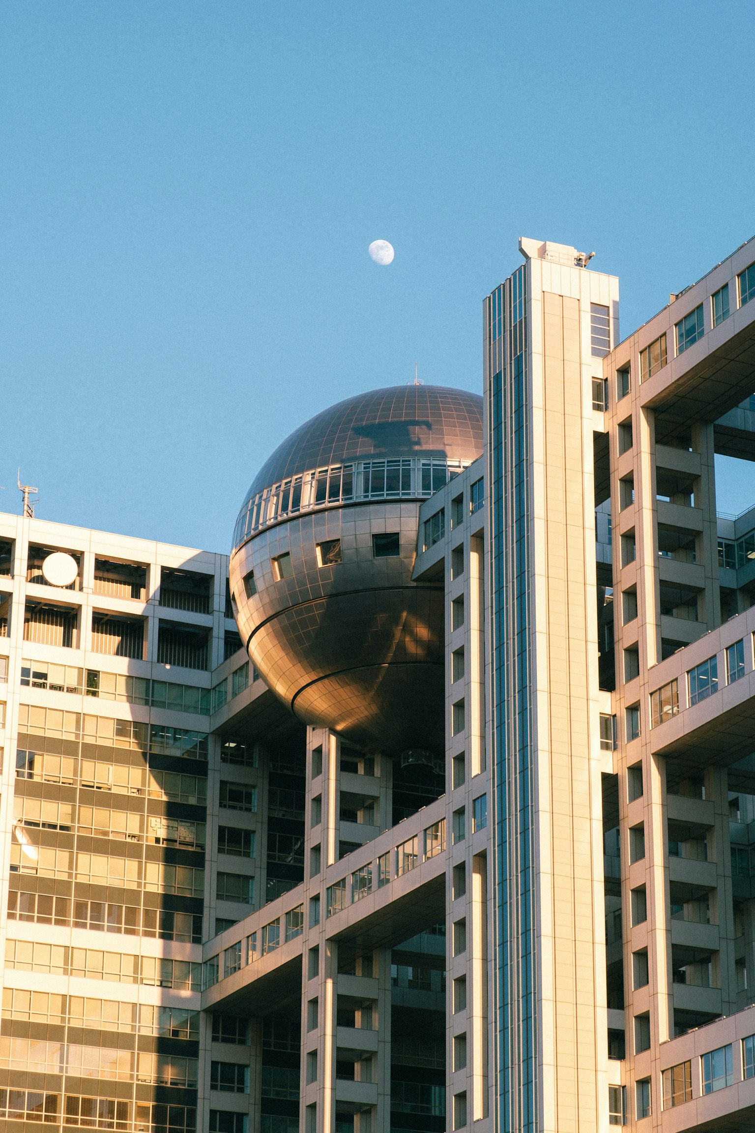 Bâtiment futuriste avec une sphère argentée sous un ciel bleu