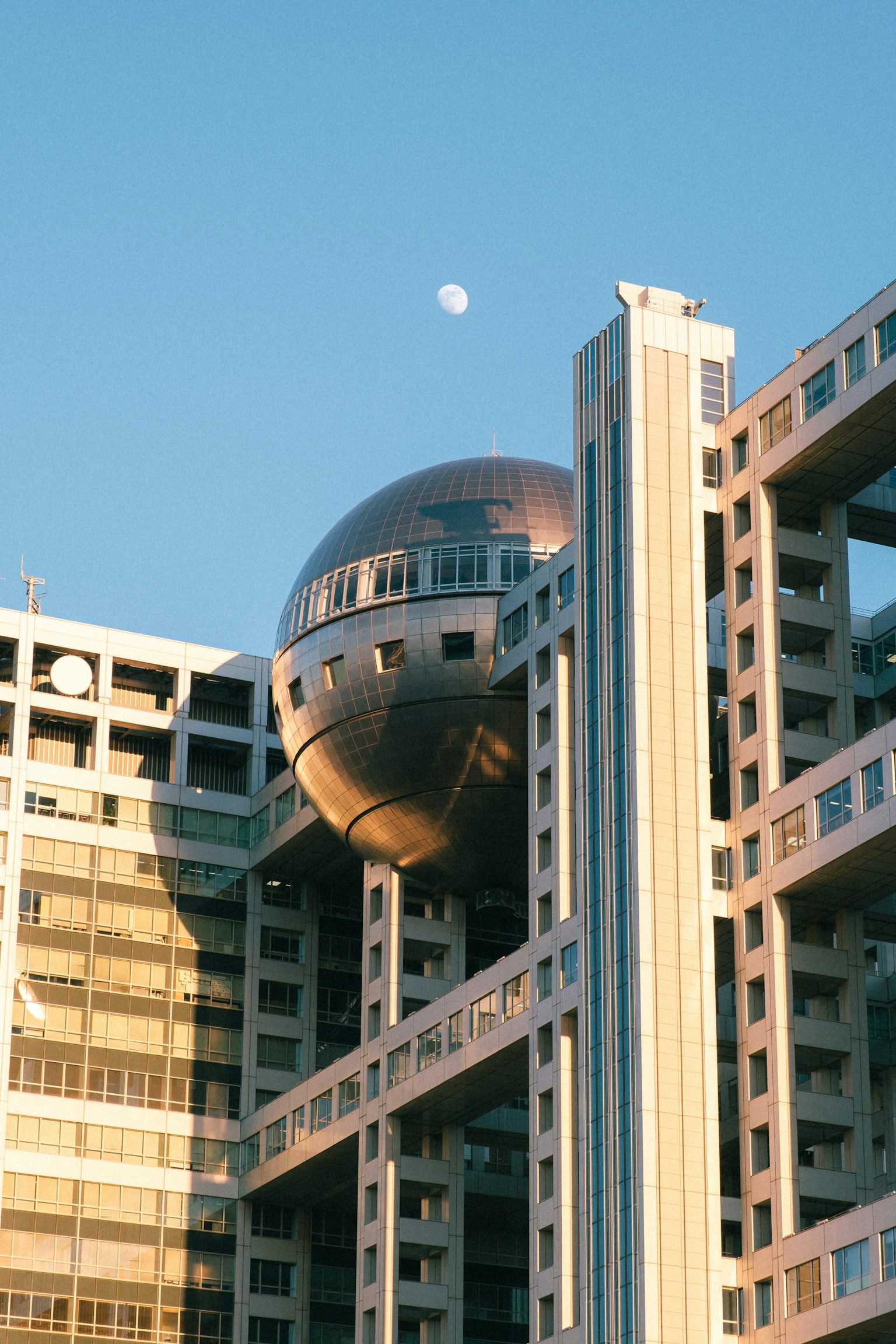 Bâtiment futuriste avec une sphère argentée sous un ciel bleu