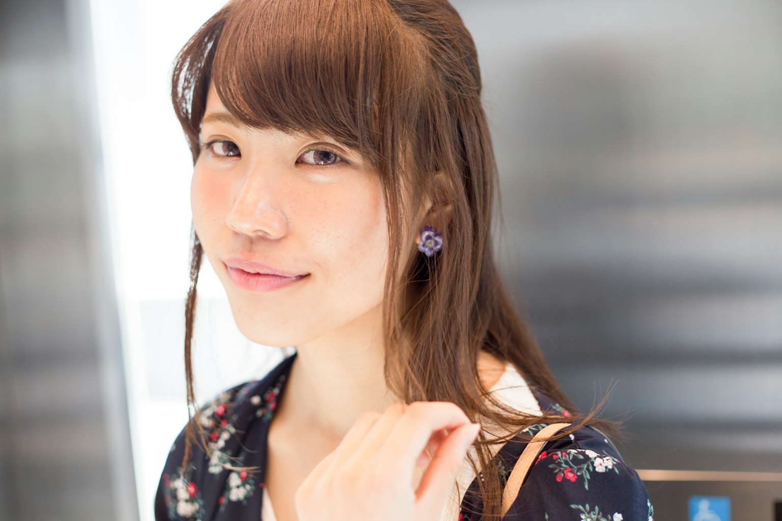 A woman with shoulder-length hair smiling wearing a floral dress