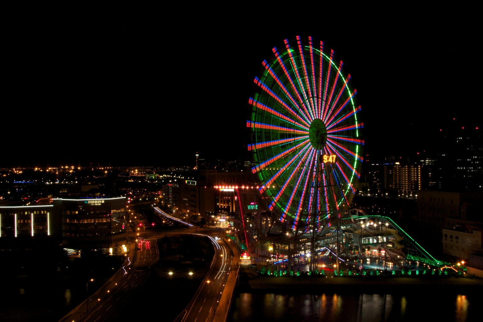 Une grande roue illuminée la nuit avec des lumières colorées