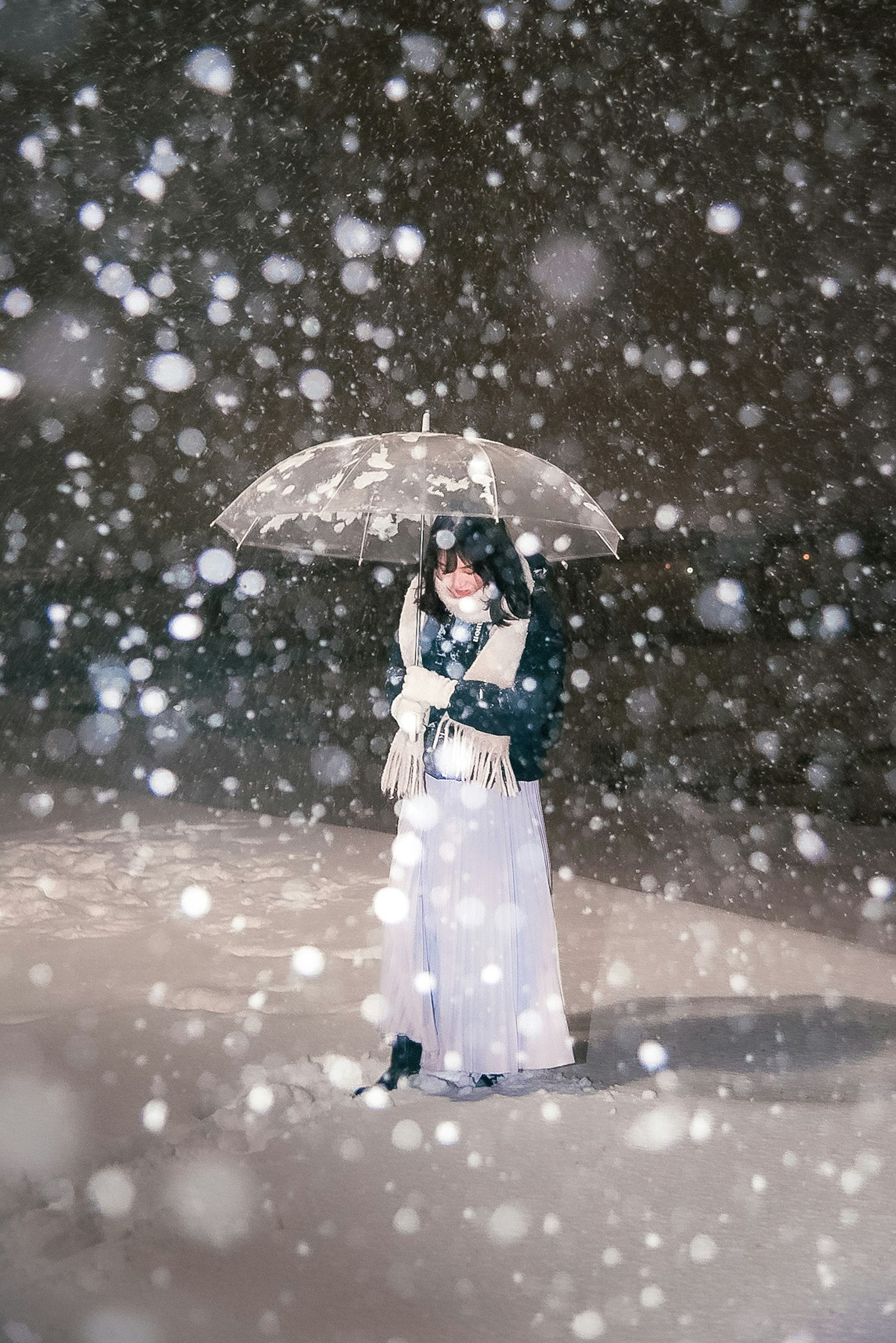 雪の中で白い傘を持つ女性の姿
