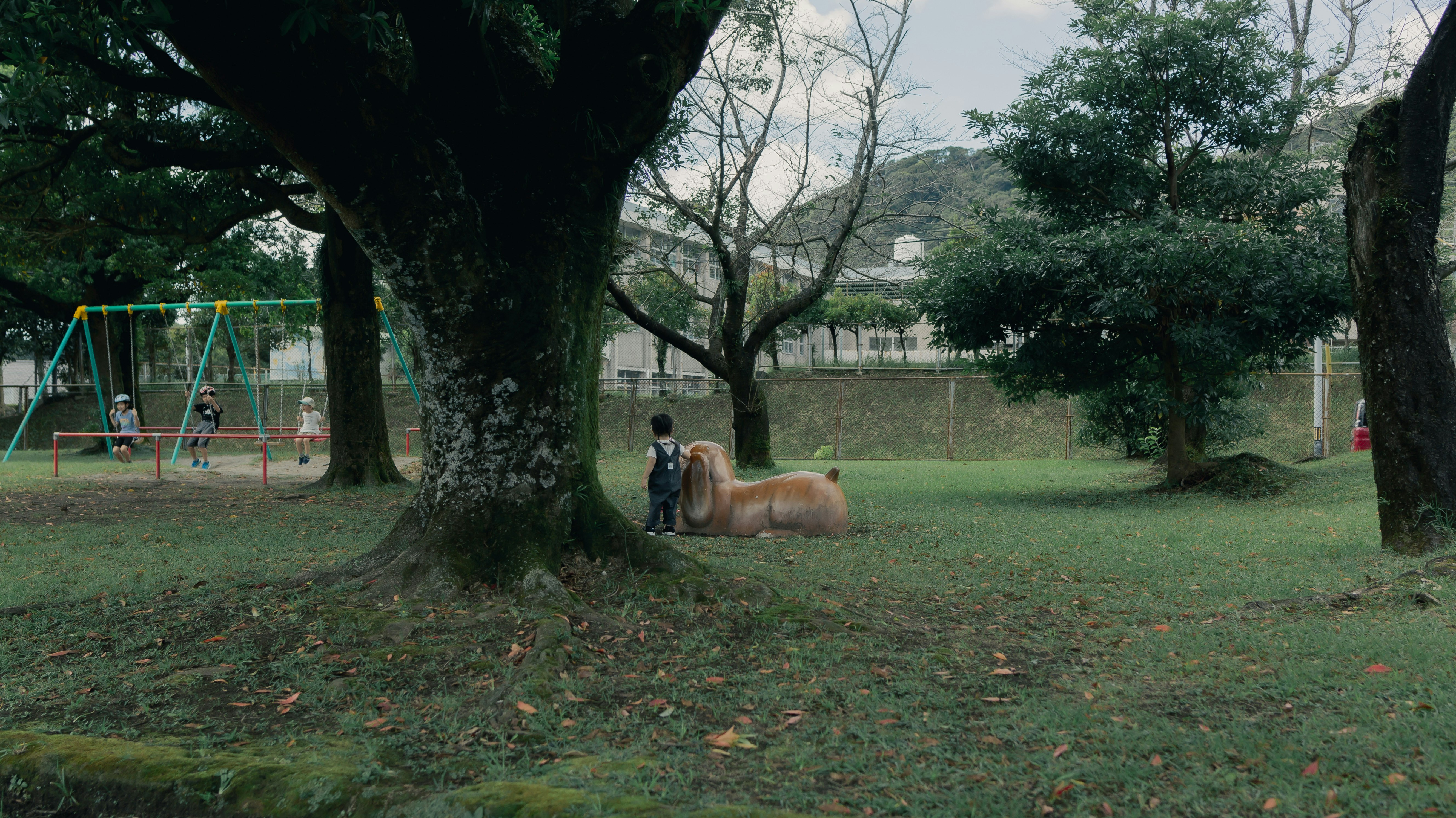 公園の芝生で遊ぶ親子と木々のある風景