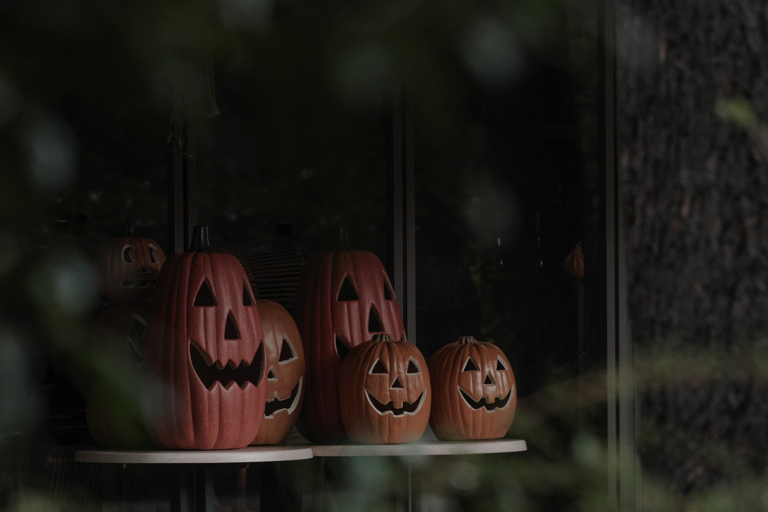Calabazas de Halloween exhibidas en un alféizar con un fondo oscuro