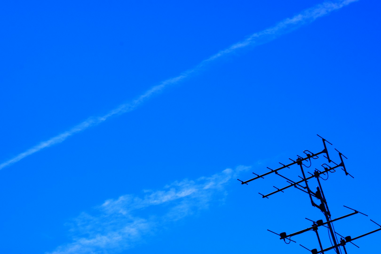 細長い雲とアンテナのある青空