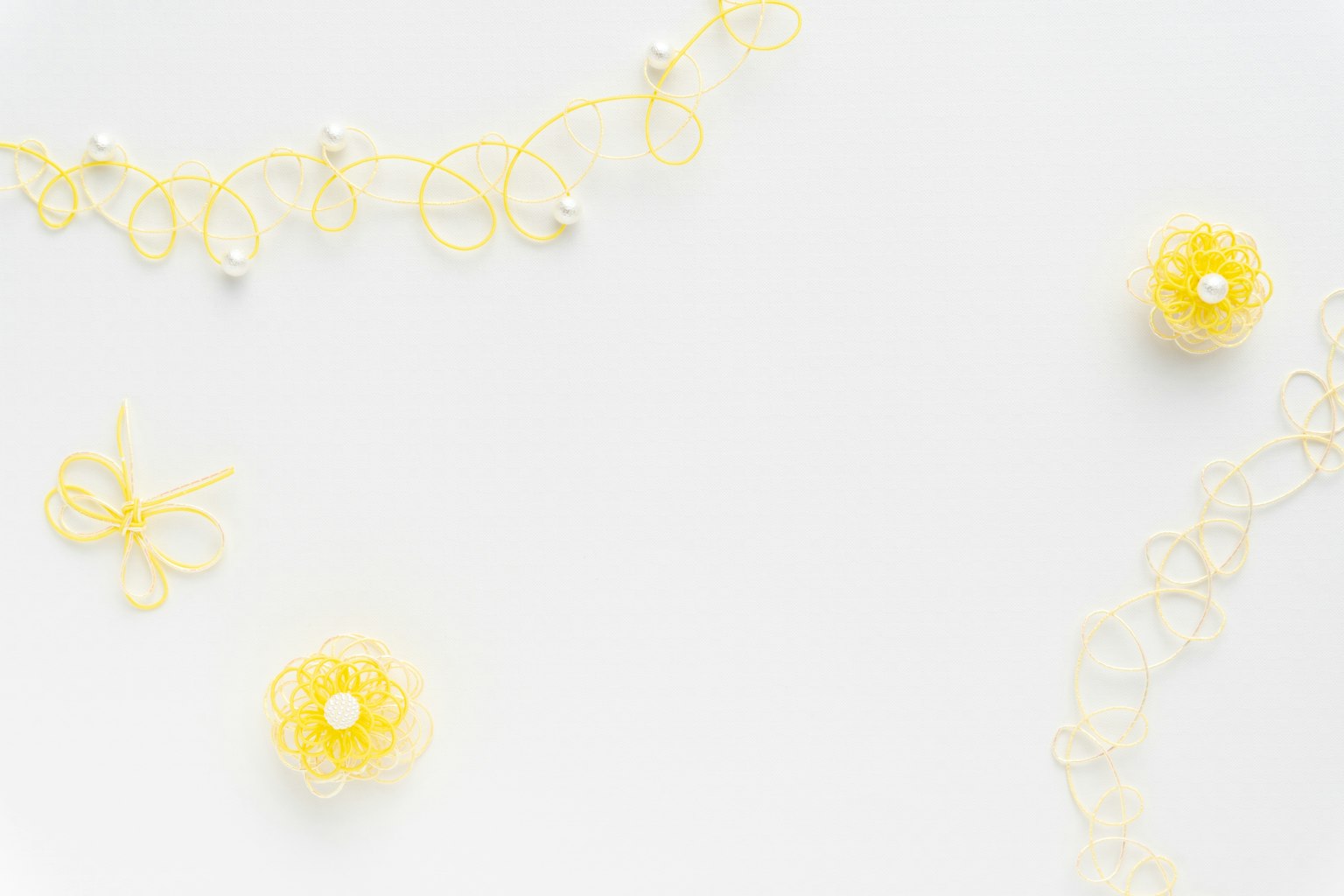 Immagine con decorazioni in pizzo giallo e perline sparse su uno sfondo bianco