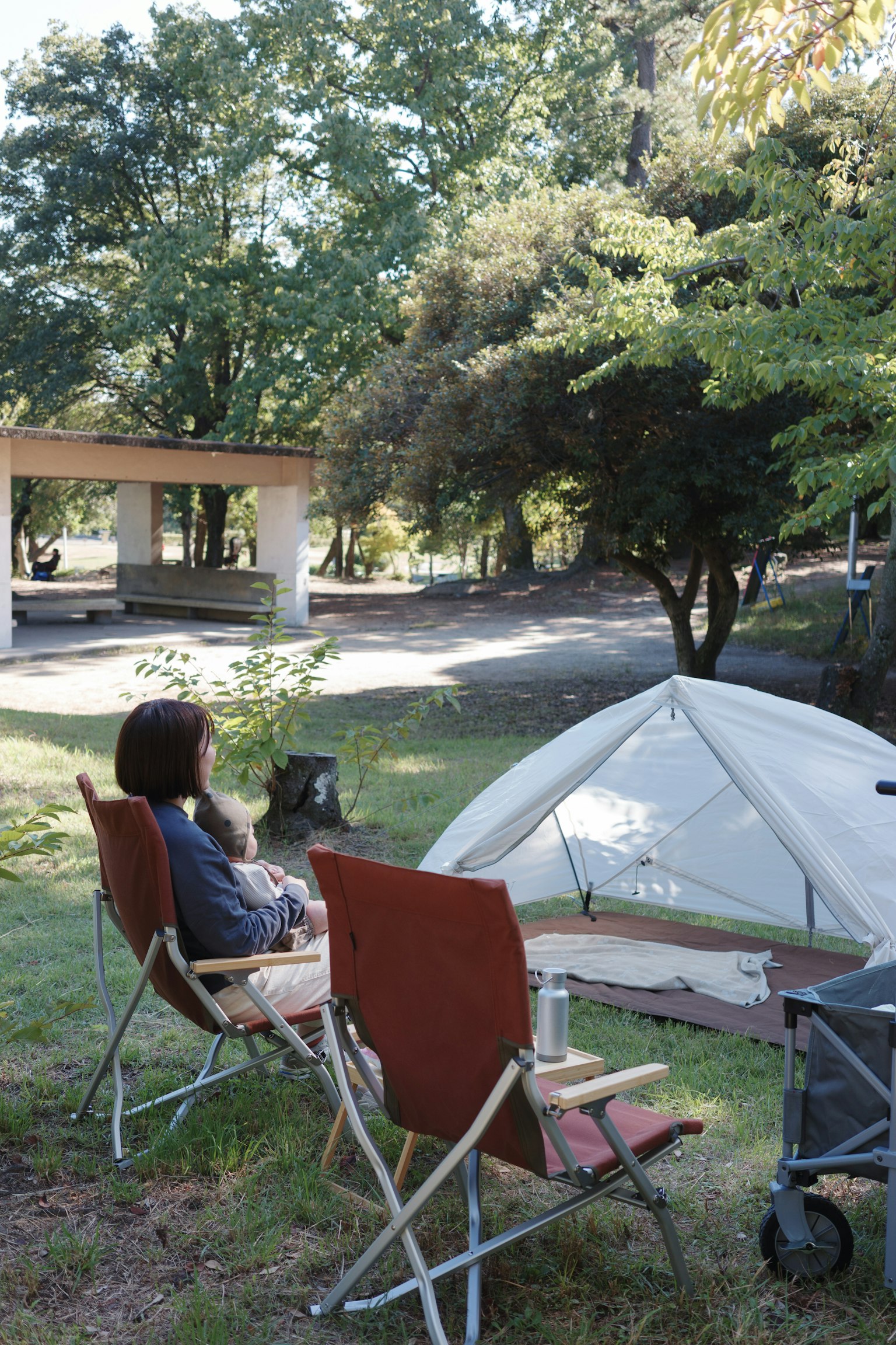 キャンプ場で椅子に座る人とテントのある風景