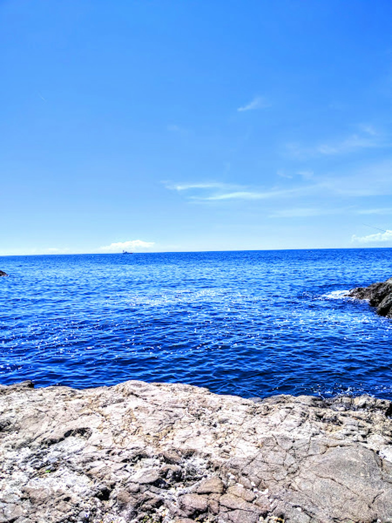 Vista panoramica di un oceano blu con una costa rocciosa sotto un cielo sereno