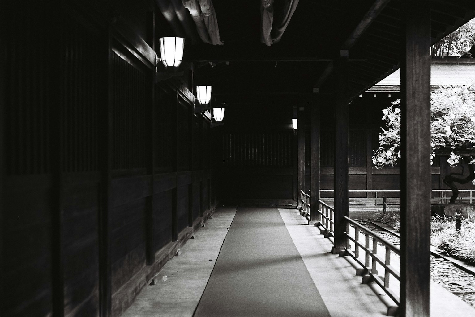 Lorong gelap dengan lentera dan pegangan kayu