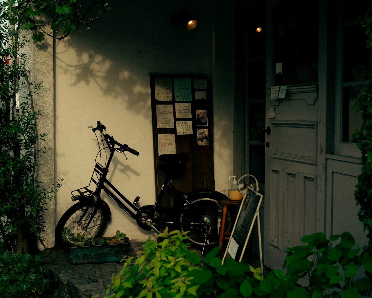 A bicycle by a cafe entrance surrounded by greenery and a serene atmosphere