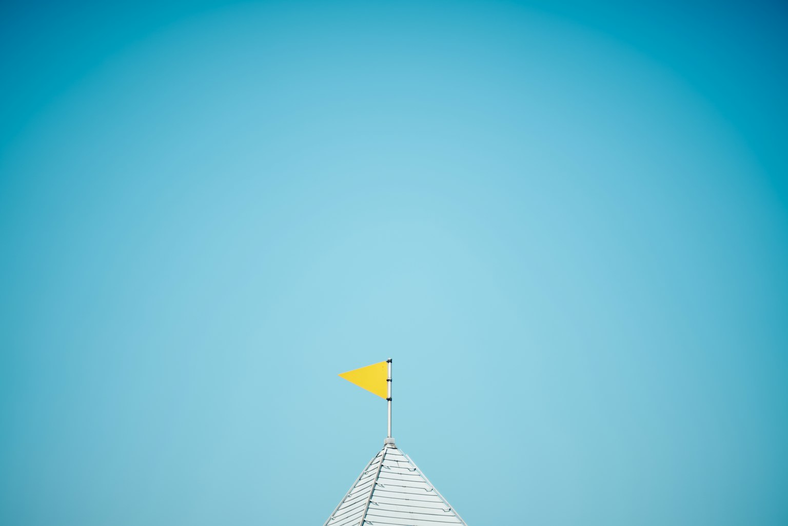 Gelbe Fahne auf einem weißen Dach unter einem klaren blauen Himmel