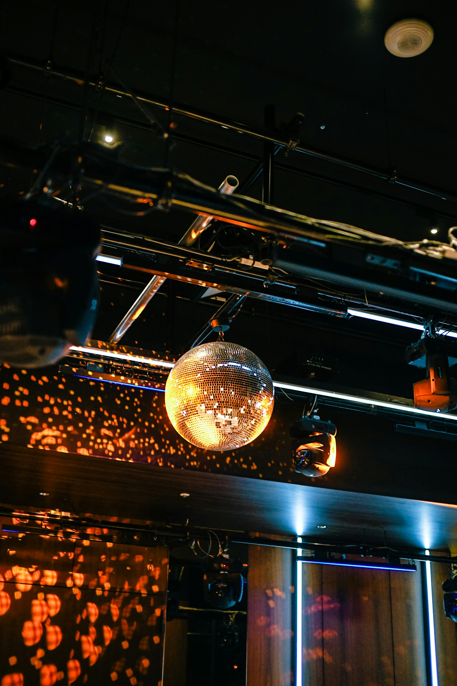 Una palla da discoteca appesa sotto le luci con uno sfondo luminoso arancione