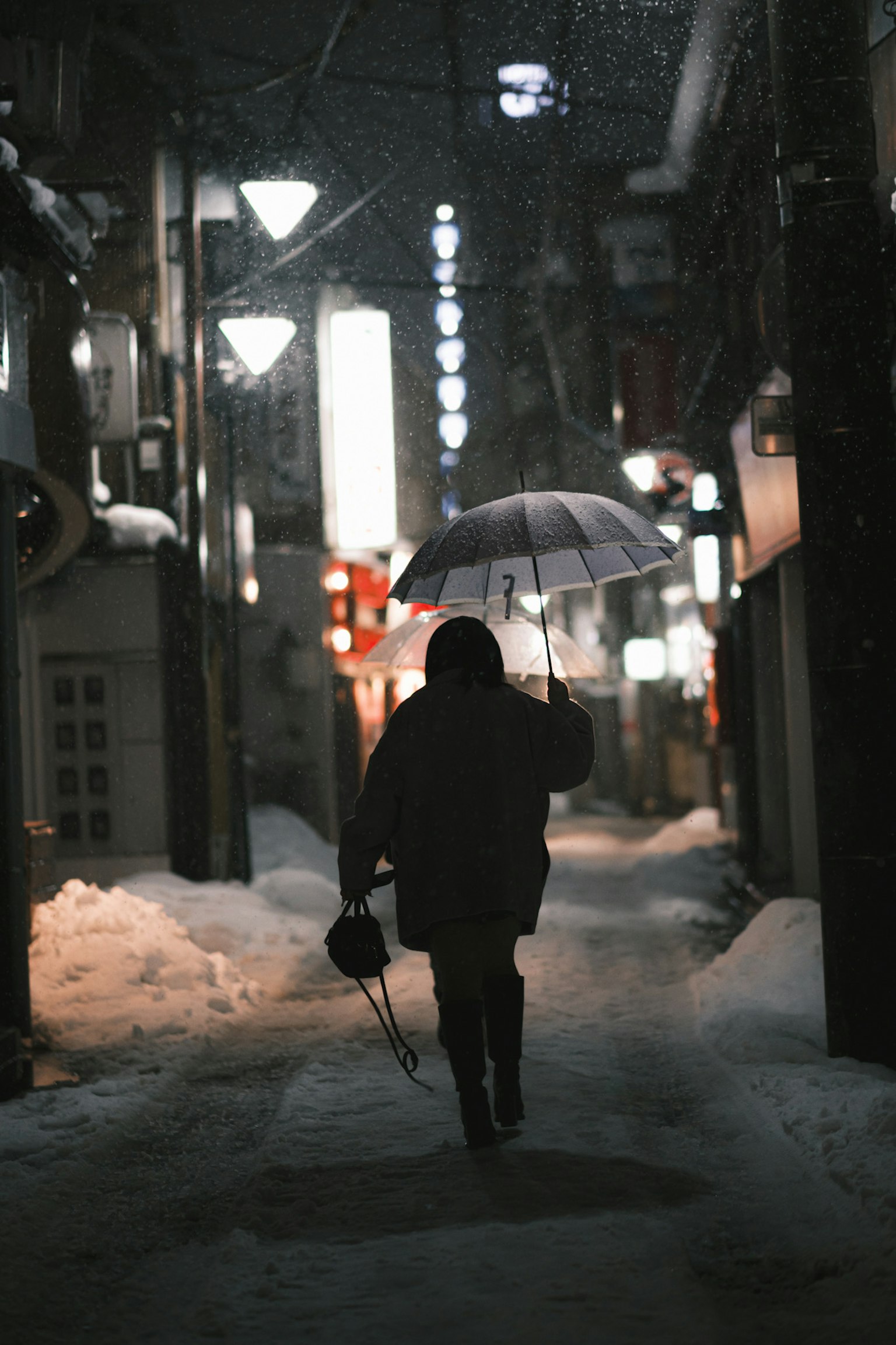 Silhouette d'une personne marchant avec un parapluie dans la neige la nuit