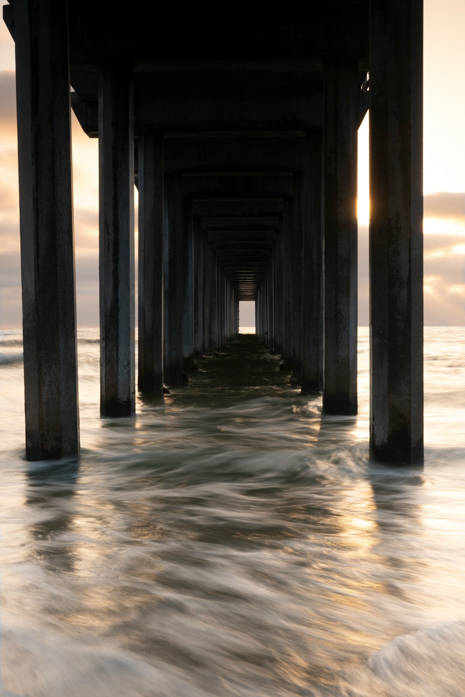 View from under a pier over the ocean with gentle waves