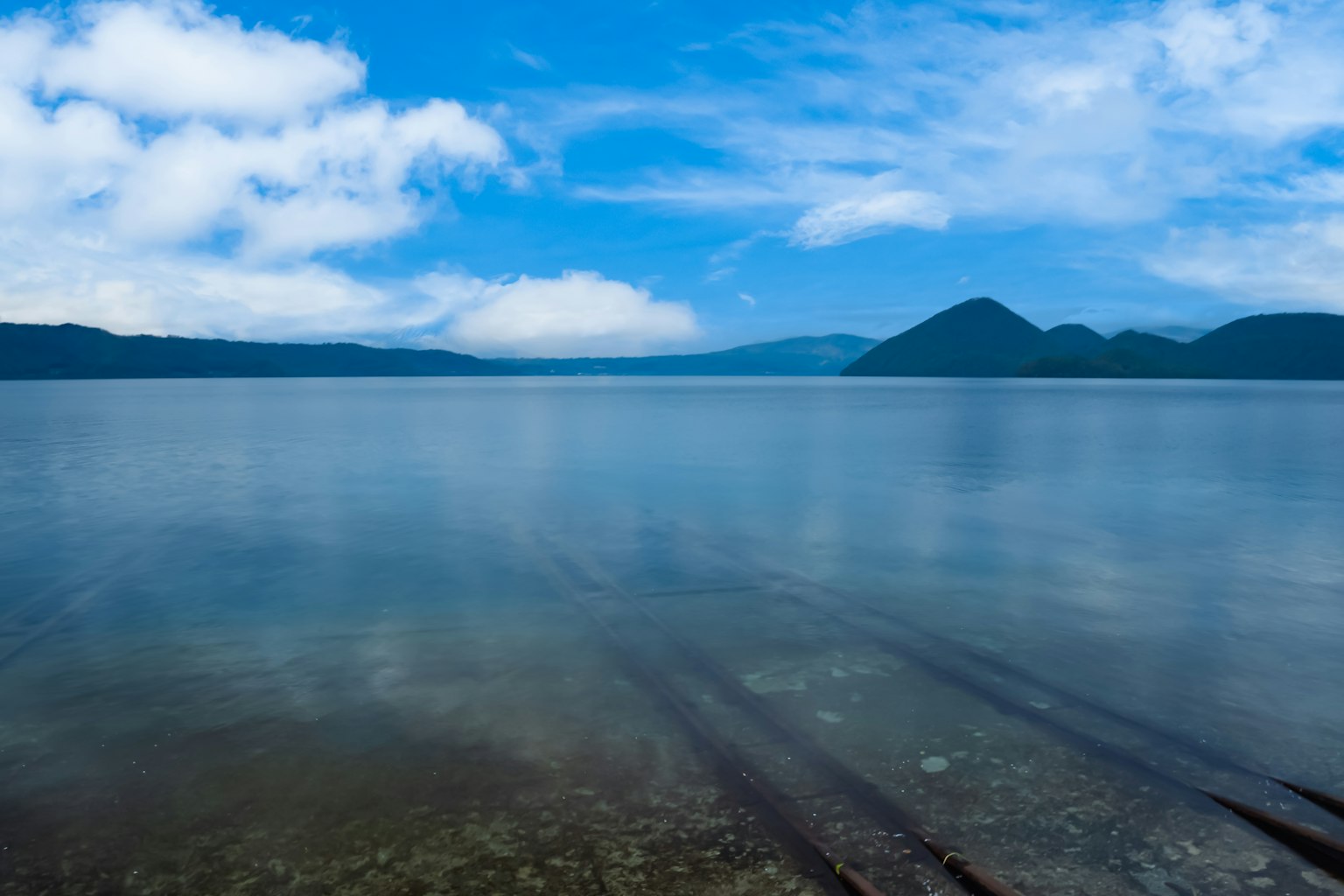 Vista escénica de un lago azul con montañas de fondo superficie de agua tranquila y nubes en el cielo
