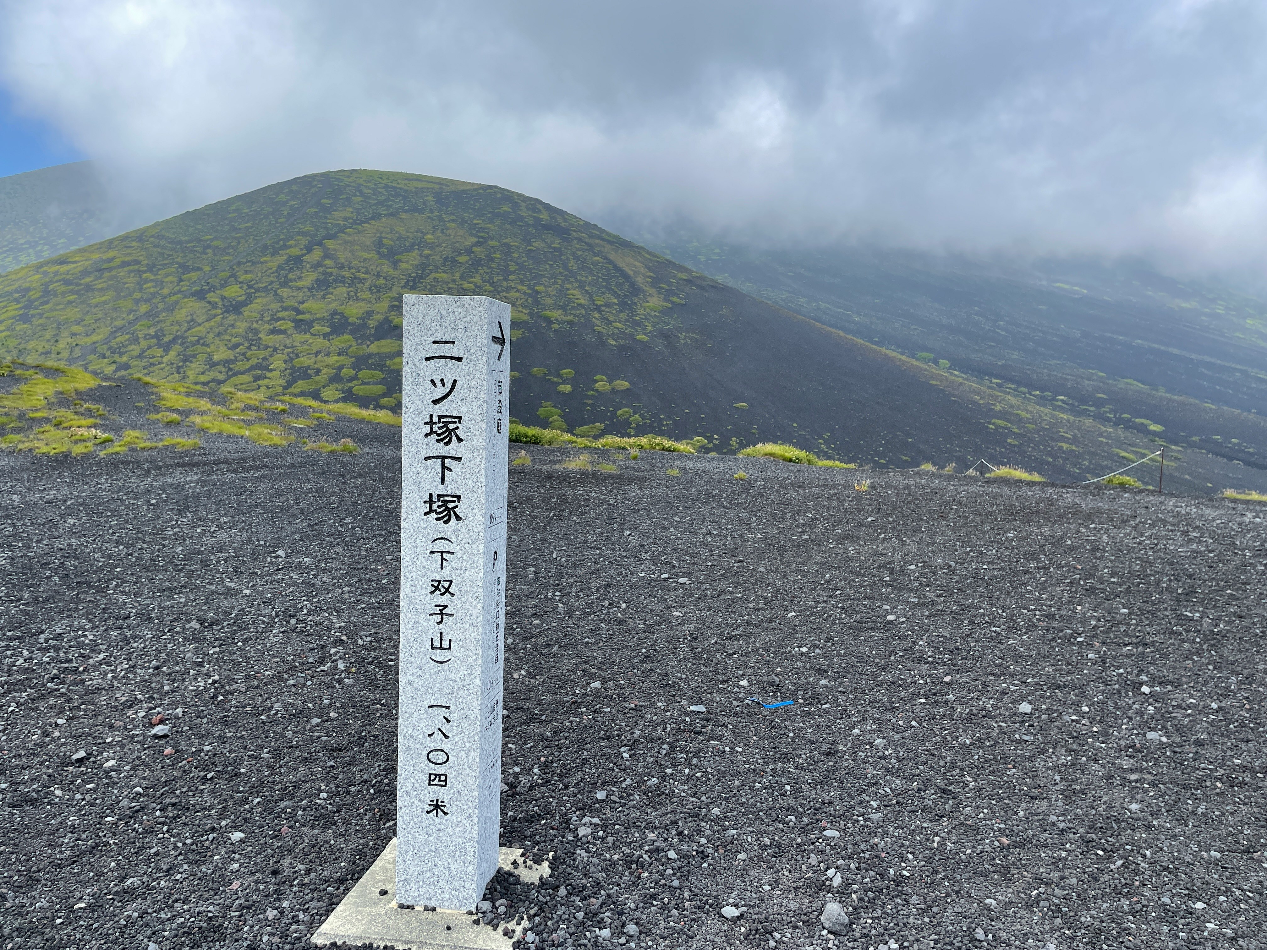 sendero de senderismo volcánico con un hito sobre suelo de lava oscura