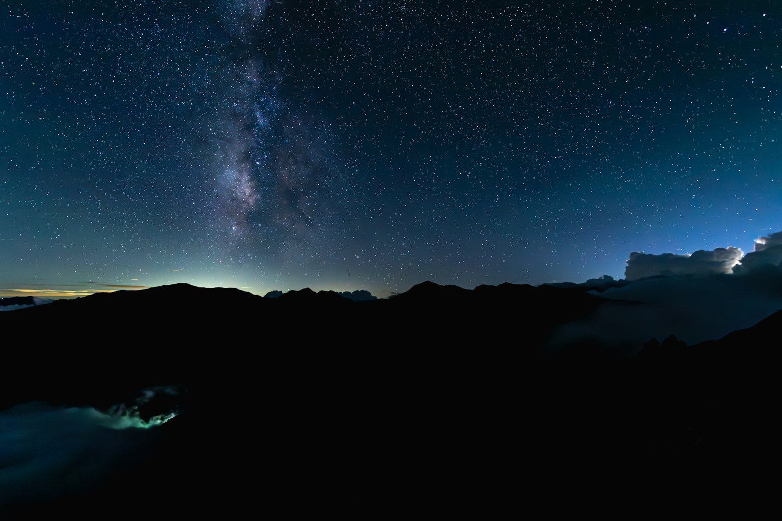 Nachlandschaft mit sternenübersätem Himmel und sichtbarer Milchstraße Bergsilhouetten