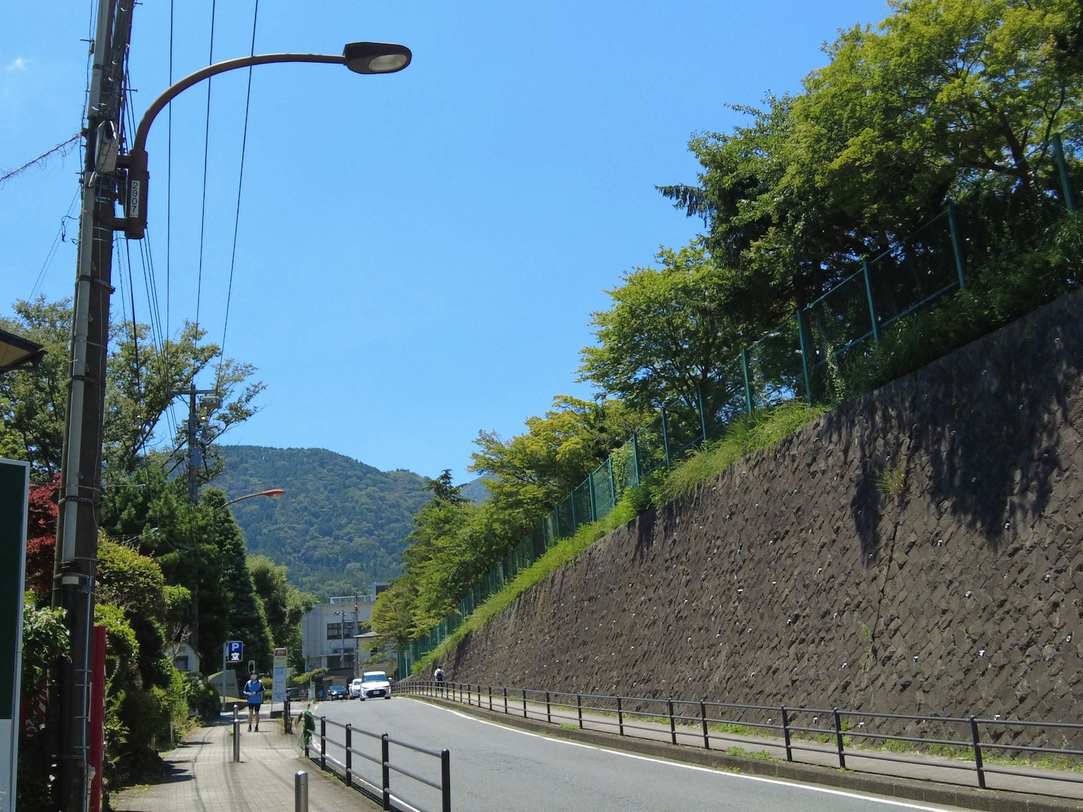 Quiet street under blue sky with lush green hillside